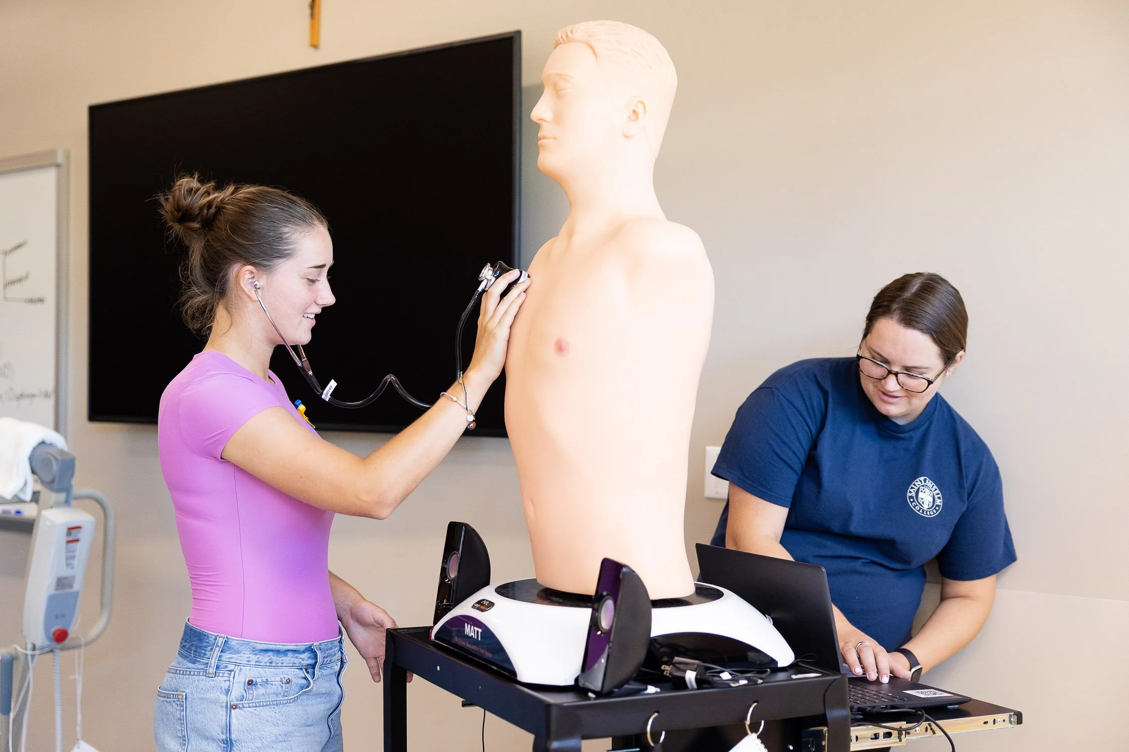 A nursing student uses a stethoscope on a medical training mannequin torso at Saint Anselm College.