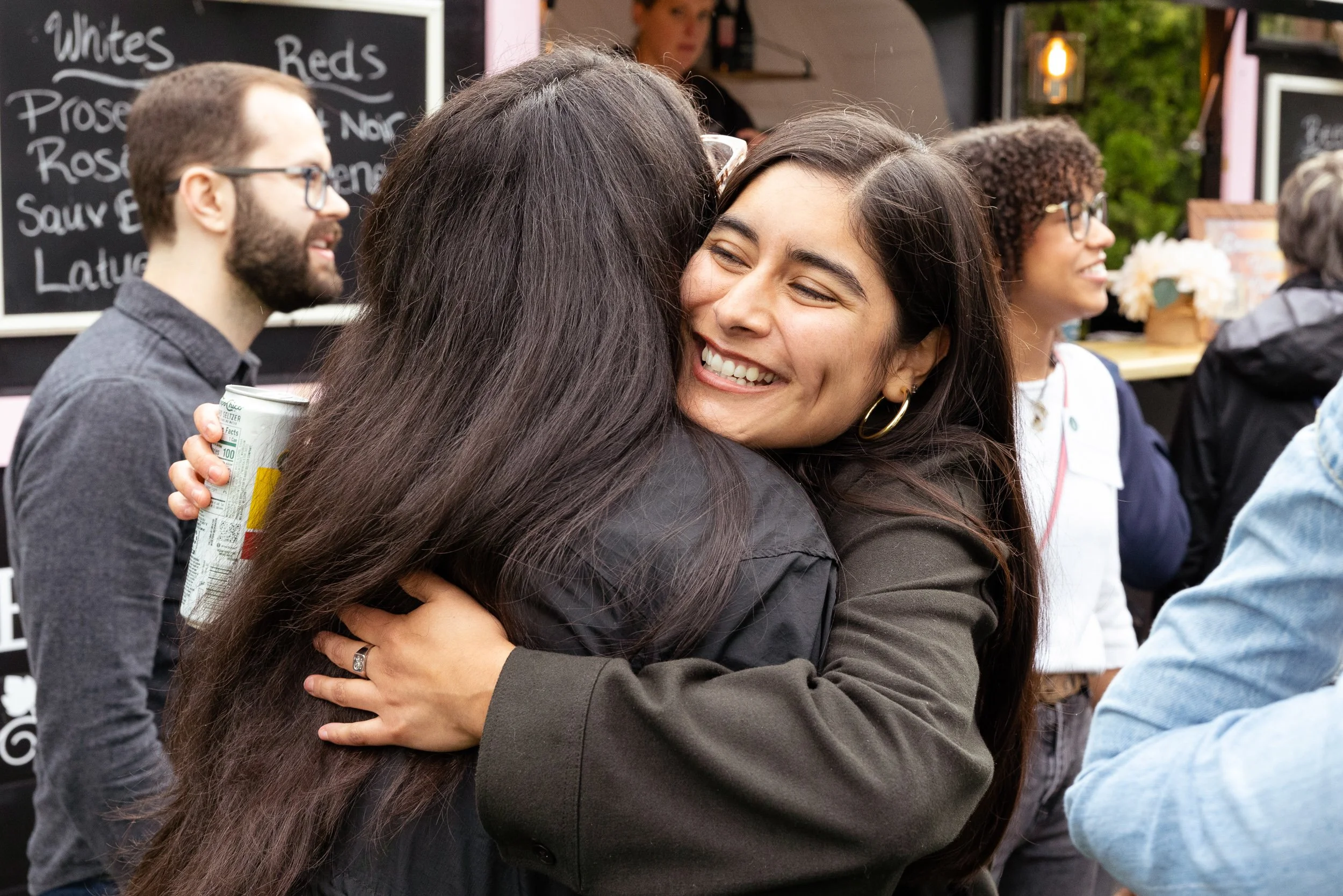 Two women hugging warmly at a high school reunion at Concord Academy.