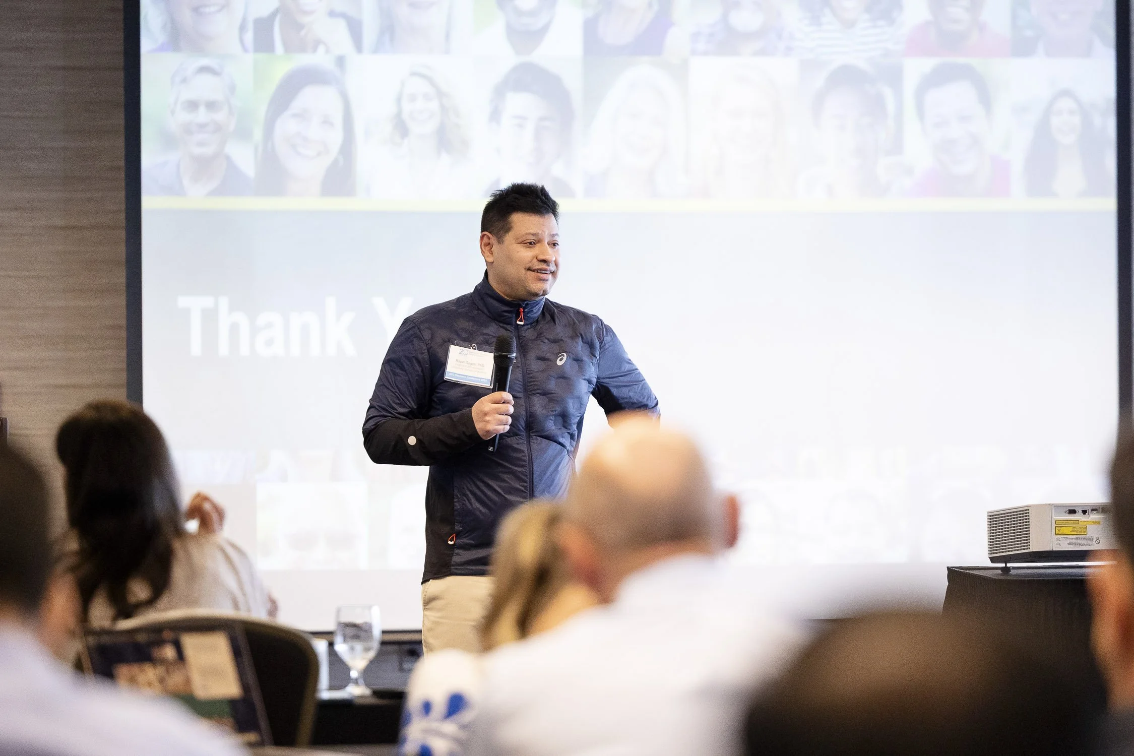 A man holding a microphone giving a presentation at a biotech conference at Mass General Hospital in Boston, Massachusetts.