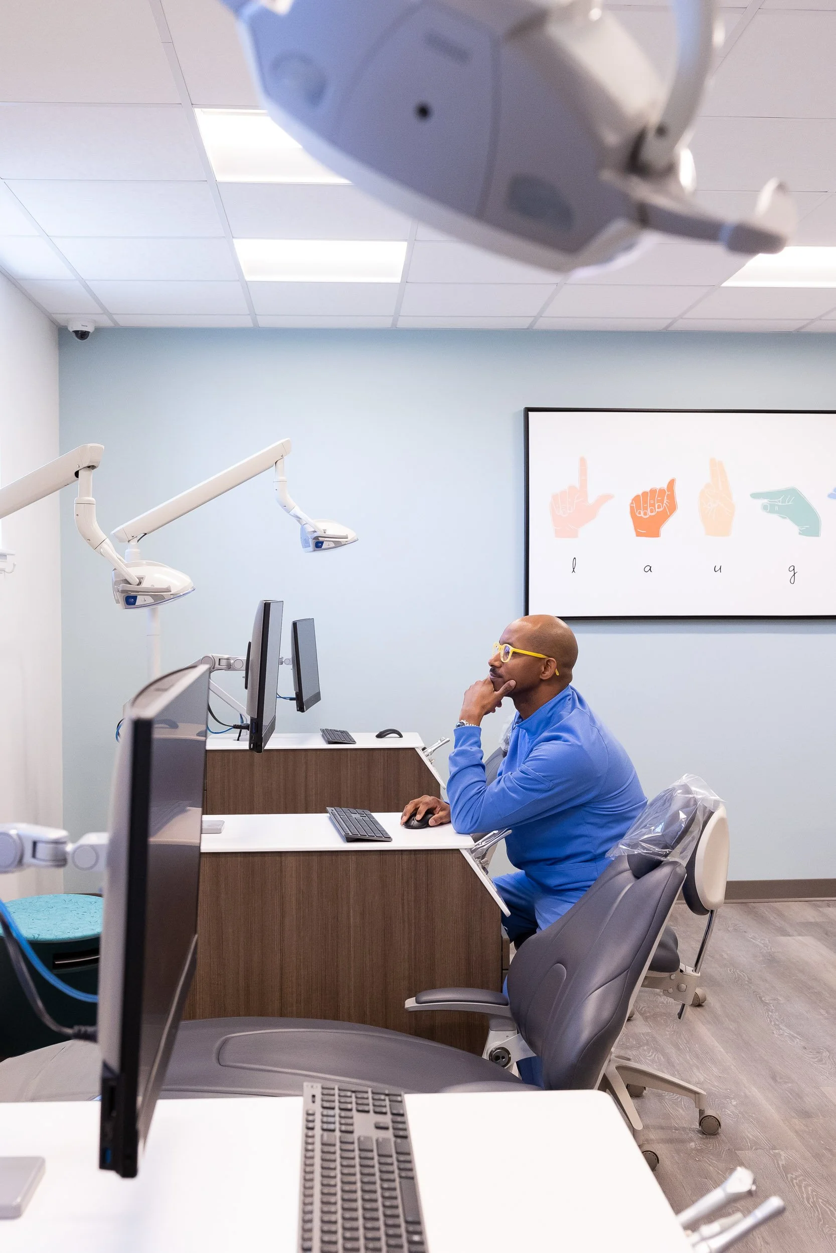 An orthodontist at a desk in a Dorchester dental office, looking at a computer monitor. 
