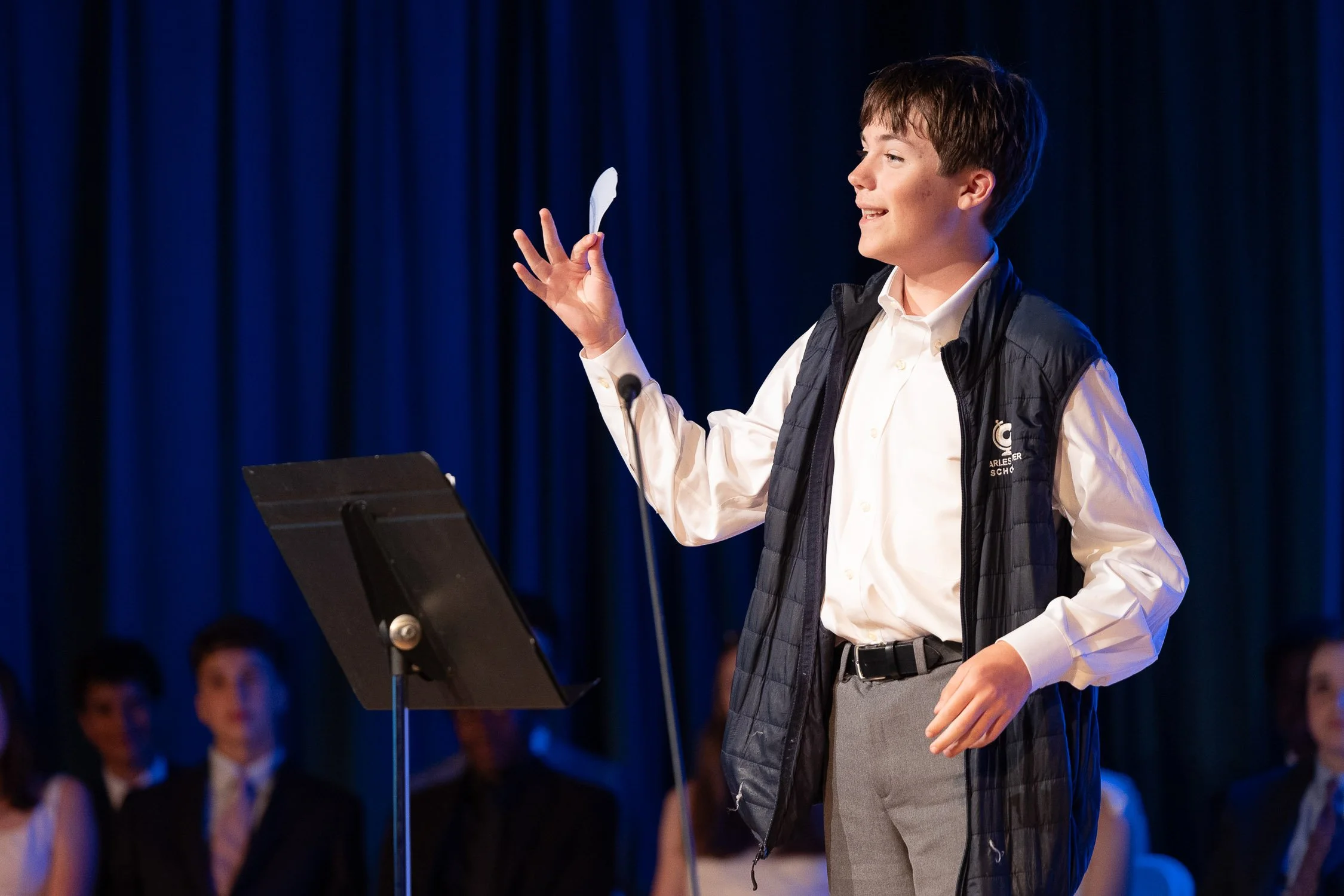 A young boy performing on stage during a middle school graduation ceremony.