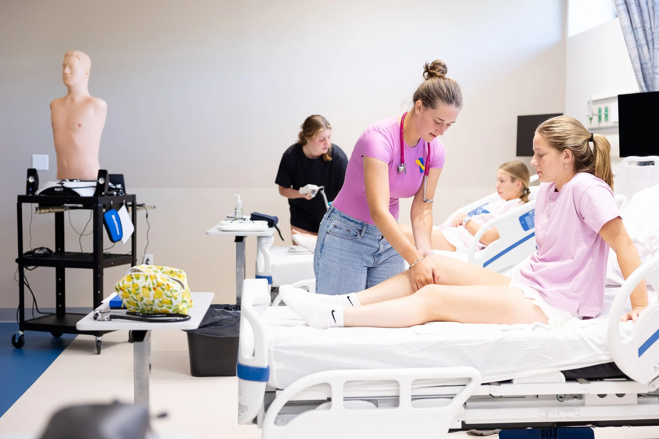 Medical training with nursing students practicing patient care on hospital beds.