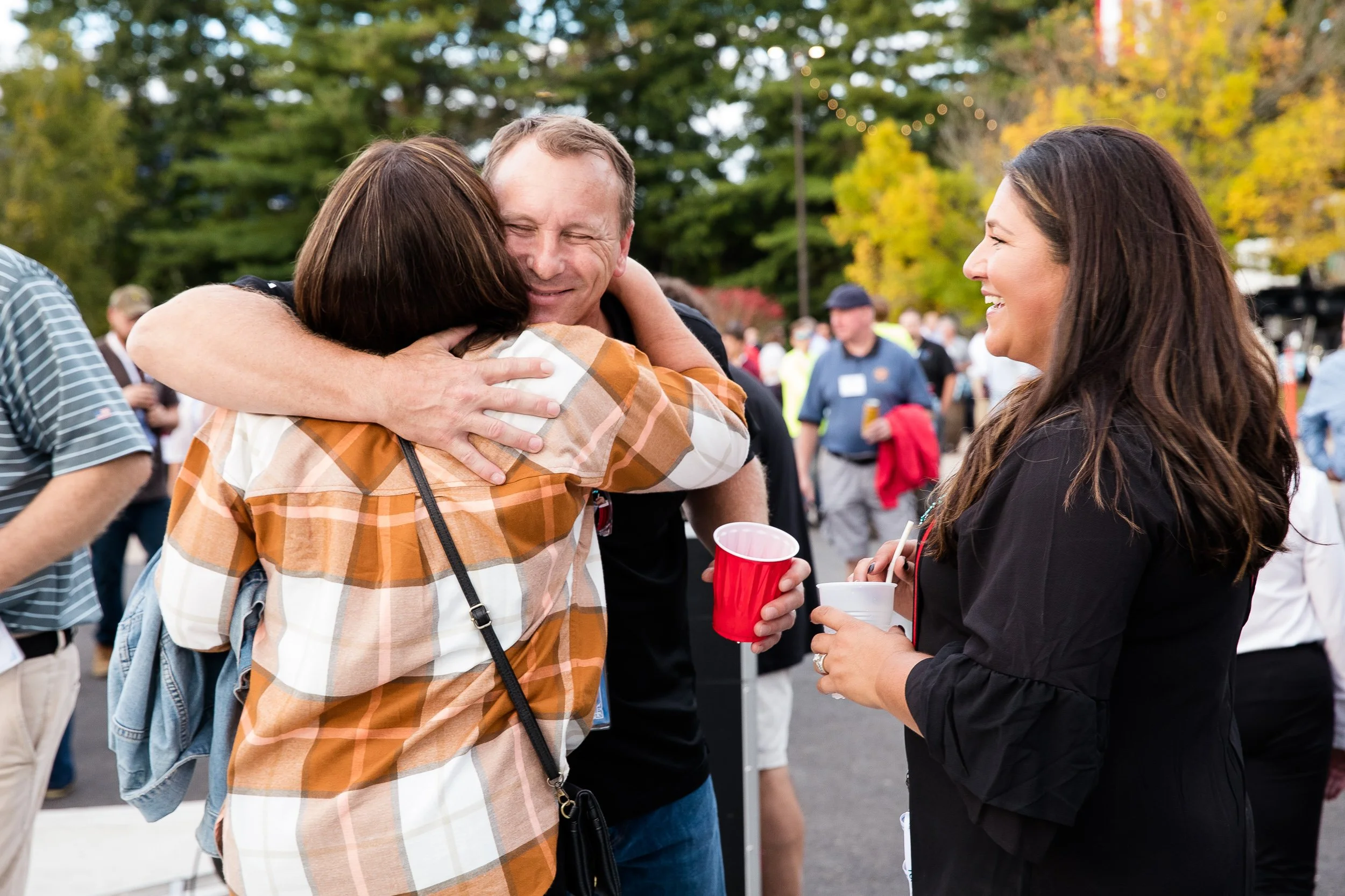 People hugging and smiling at an outdoor  at an Oktoberfest event.