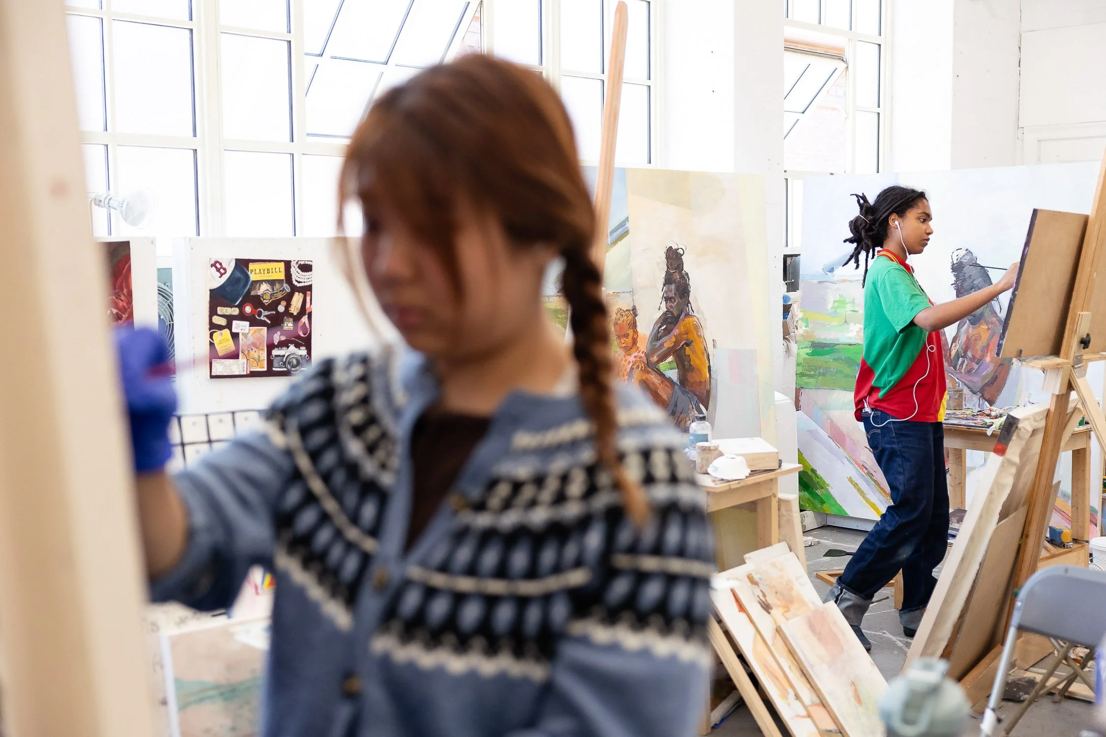 Two students painting in an art studio with large windows at RISD.