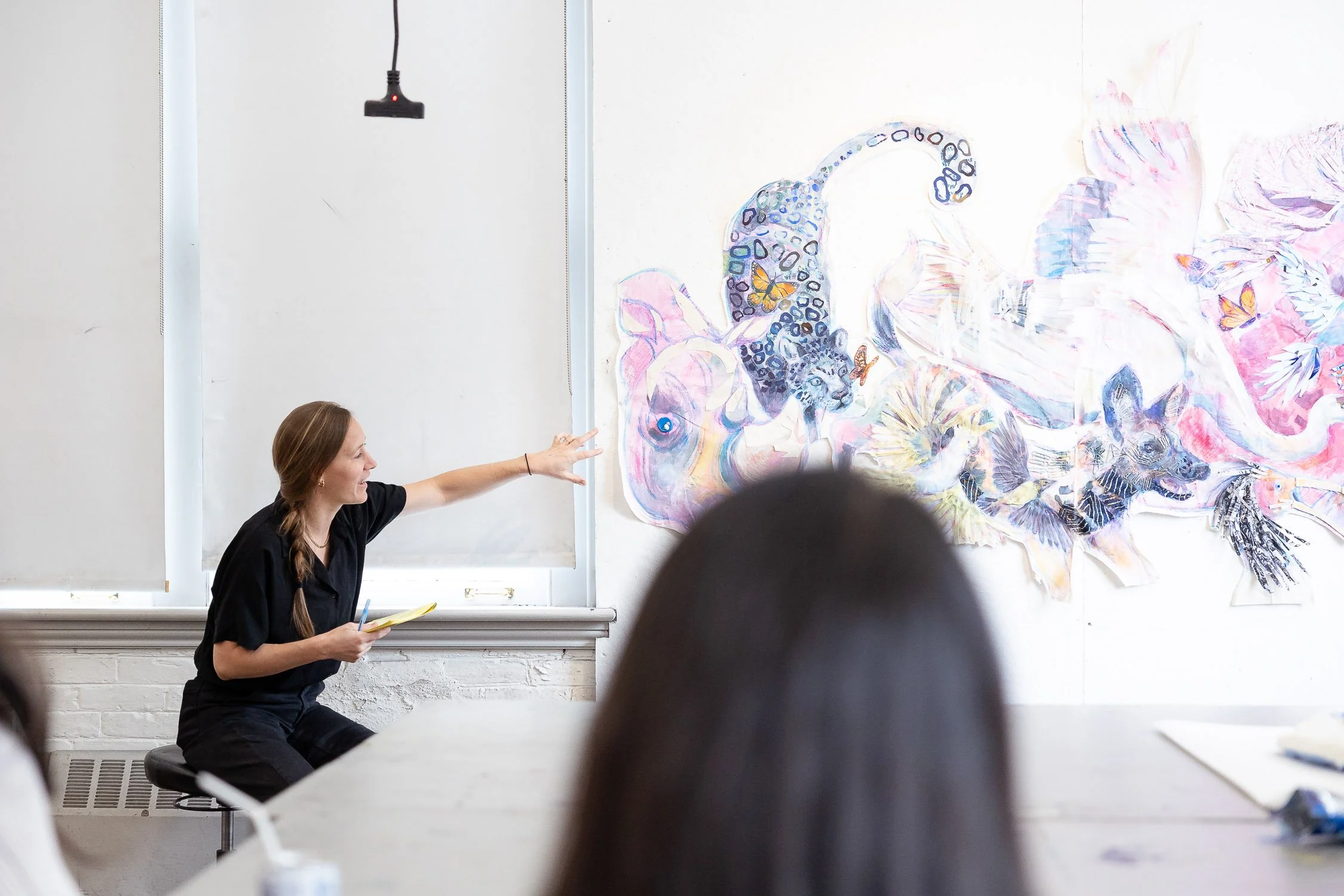 An instructor gesturing to a colorful animal mural in a classroom critique at RISD.
