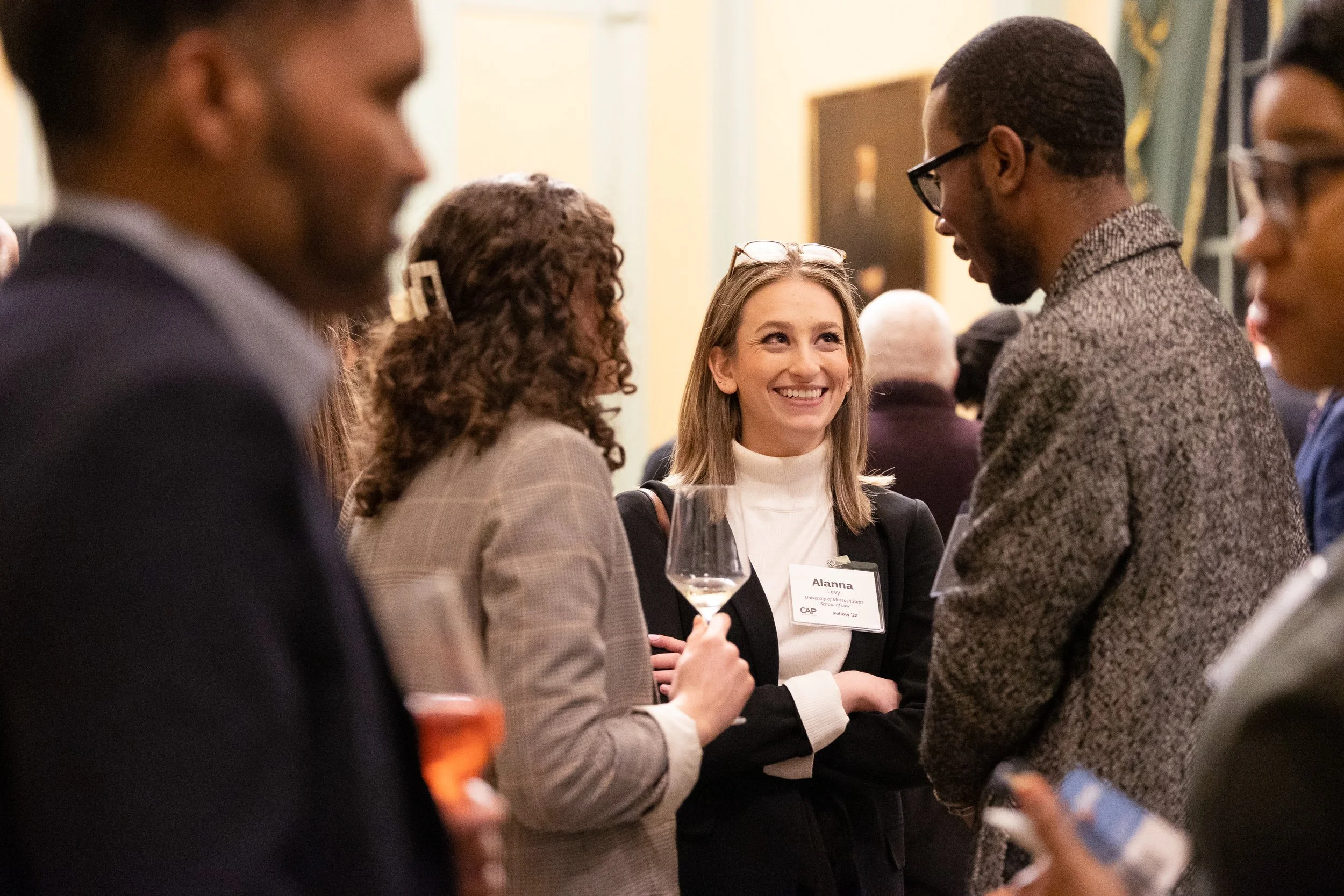 A group of people at a professional networking event, engaging in conversation, at the Massachusetts State House in Boston.
