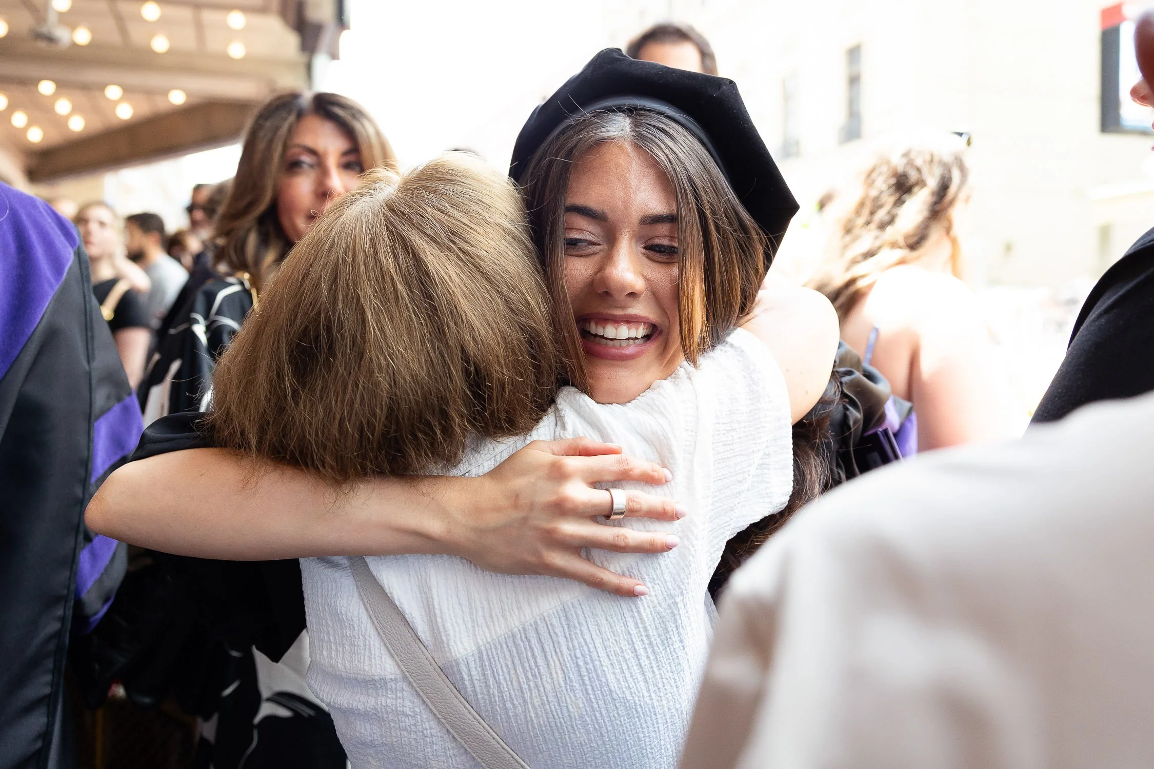 Two women hugging after a law school graduation ceremony in Boston.