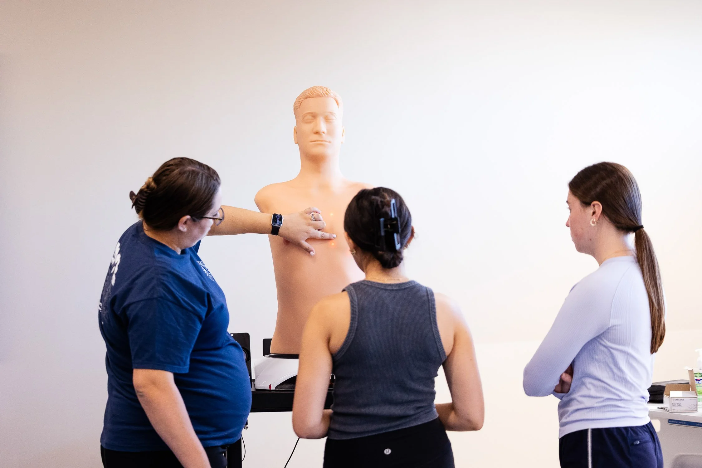 A program instructor at a New Hampshire college demonstrates a medical mannequin to two nursing studengs. 