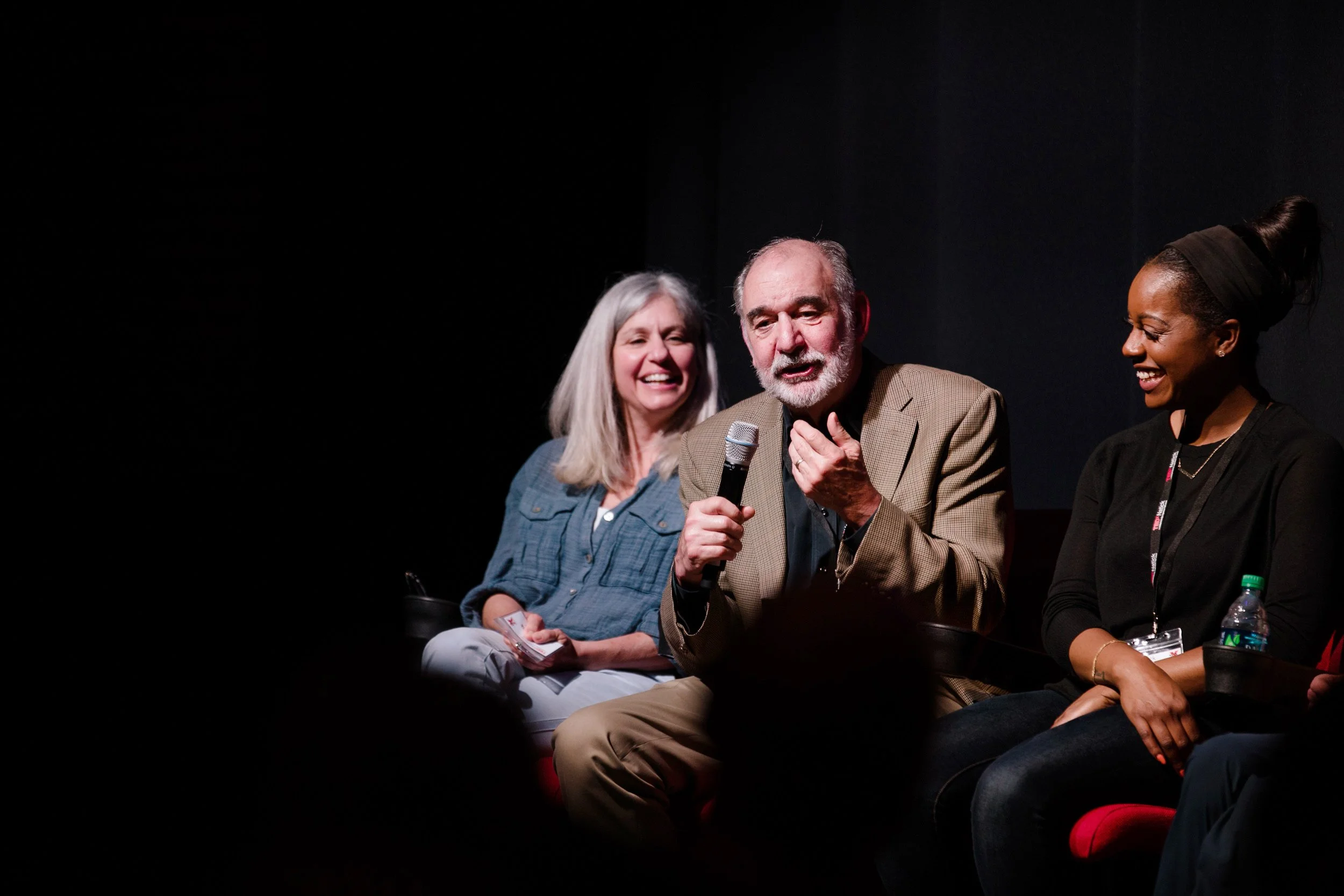 Three people sitting on a panel at a dark event at TCAN in Natick.