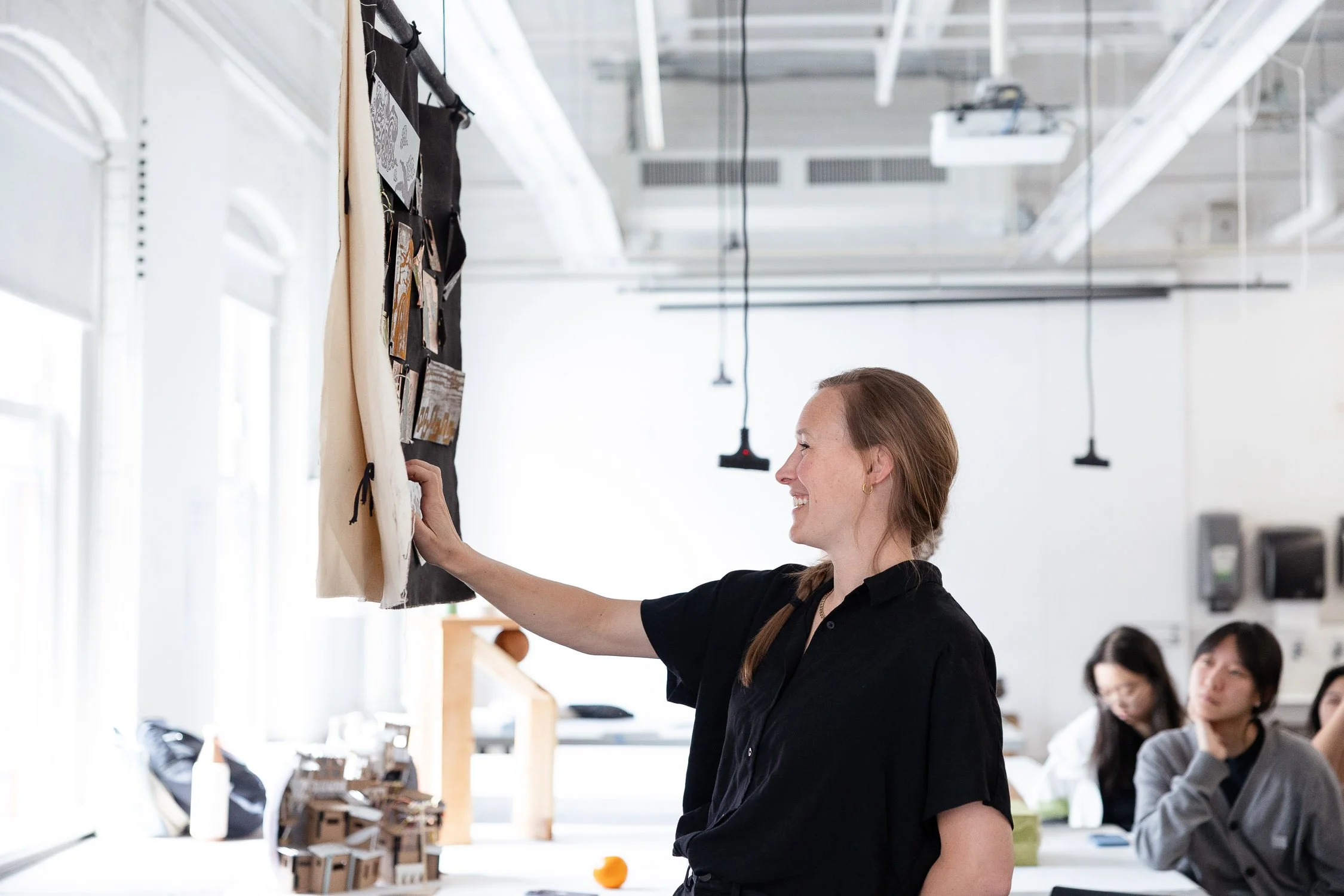 An art teacher gesturing to a hanging piece of fabric during critique at Rhode Island School of Design.
