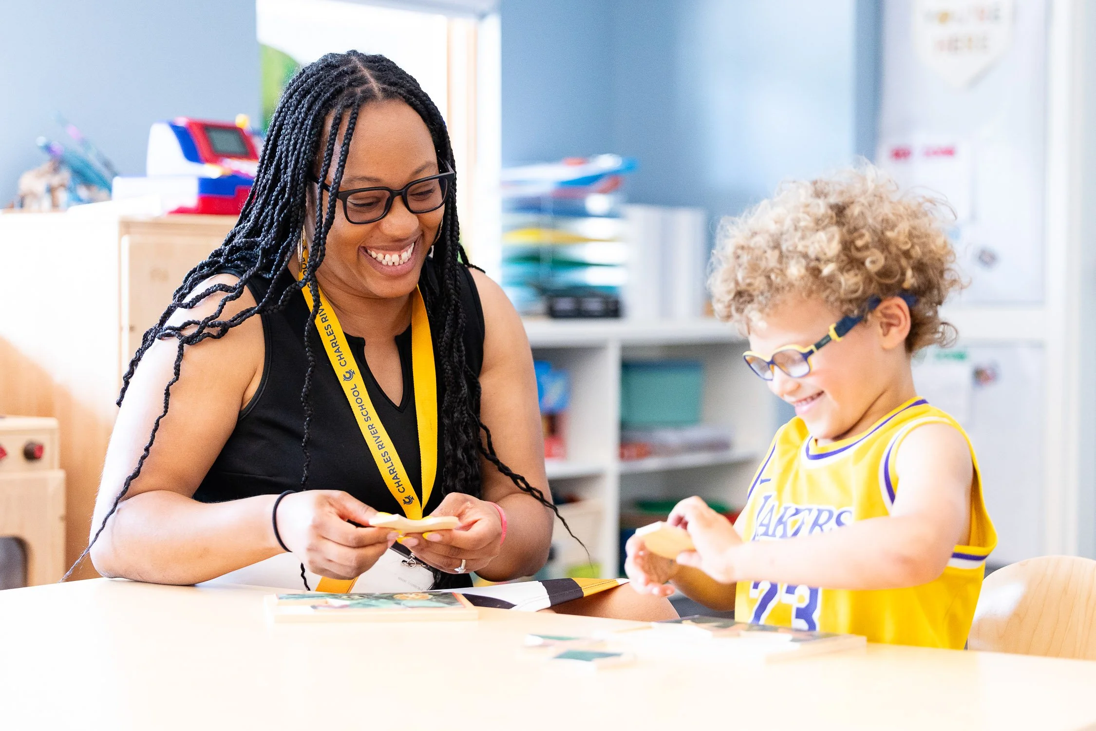 Teacher and preschool student sitting at table doing puzzle