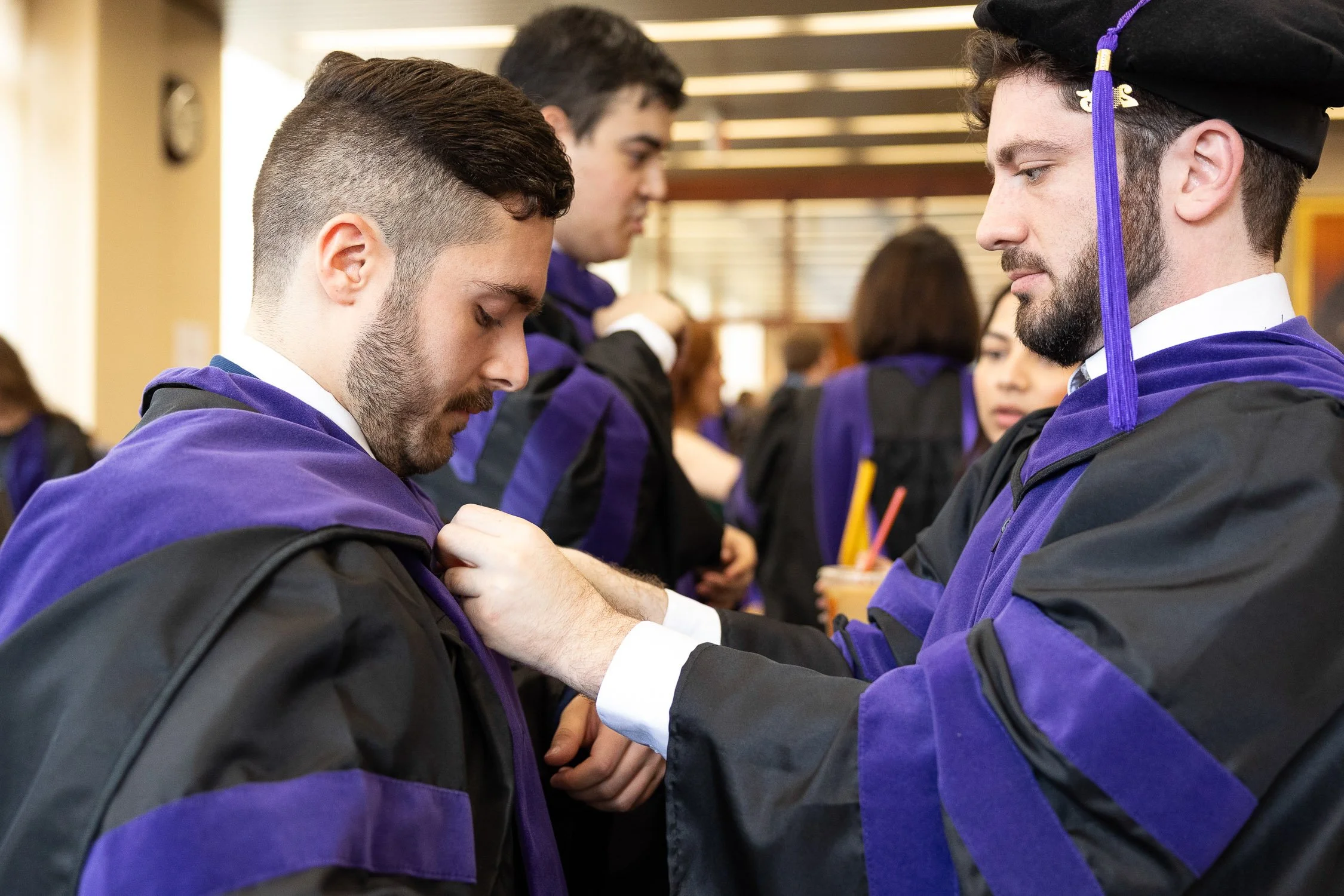 Two men in graduation caps and gowns preparing for ceremony at Boston law school.