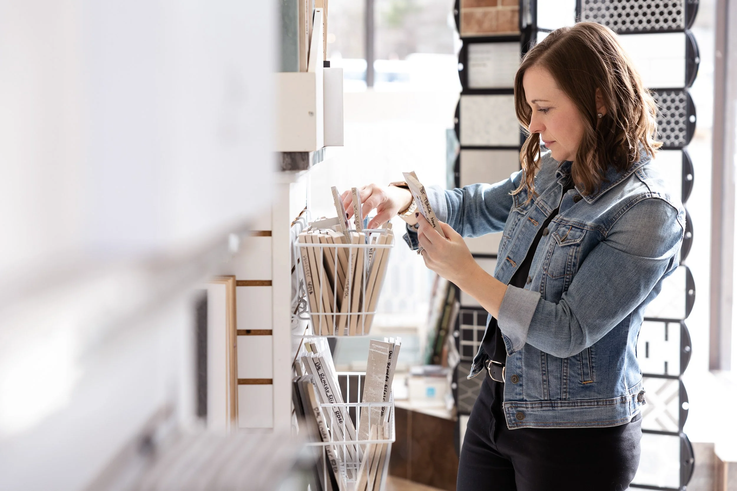 Female interior designe shopping in a tile store in Natick, Massachusetts, looking at products in a display rack.