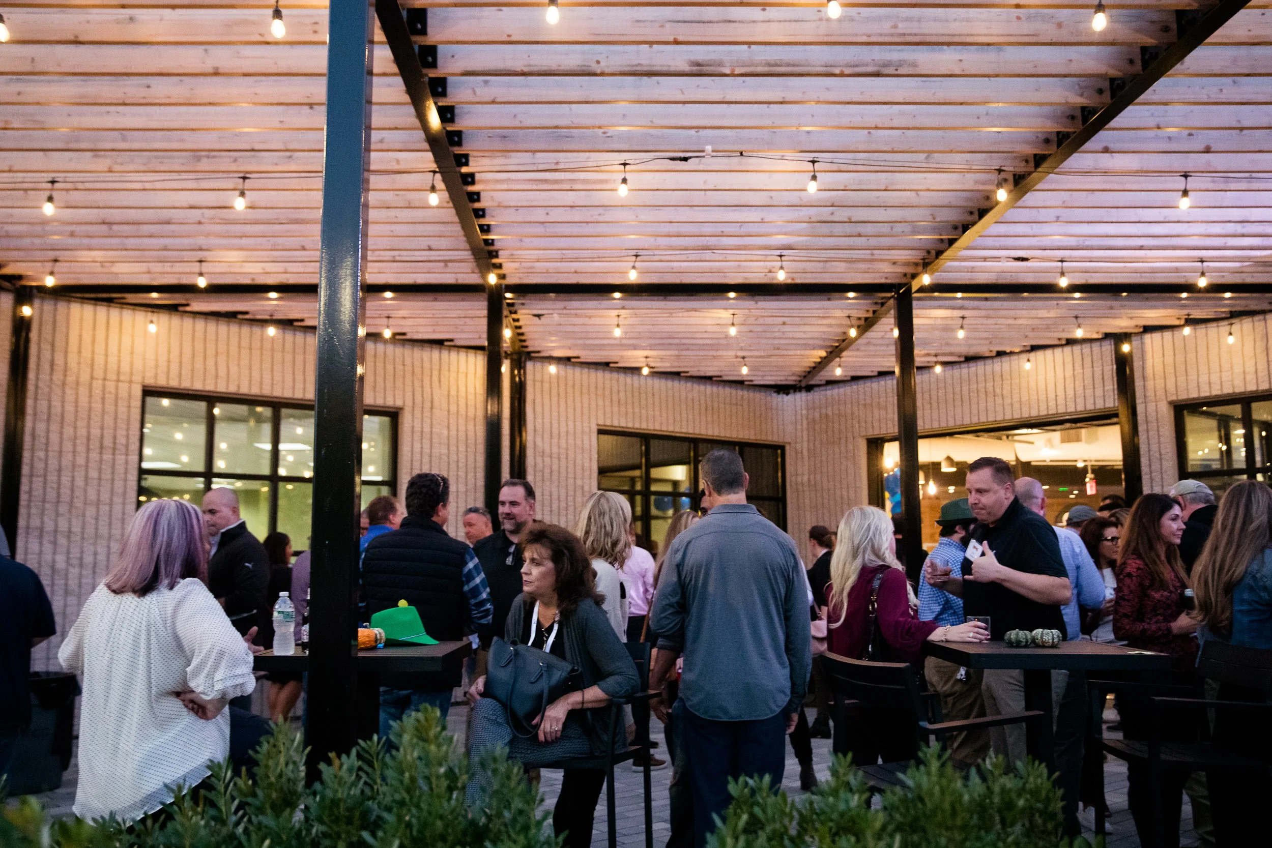 People gathered at an outdoor company party under string lights in Boston.