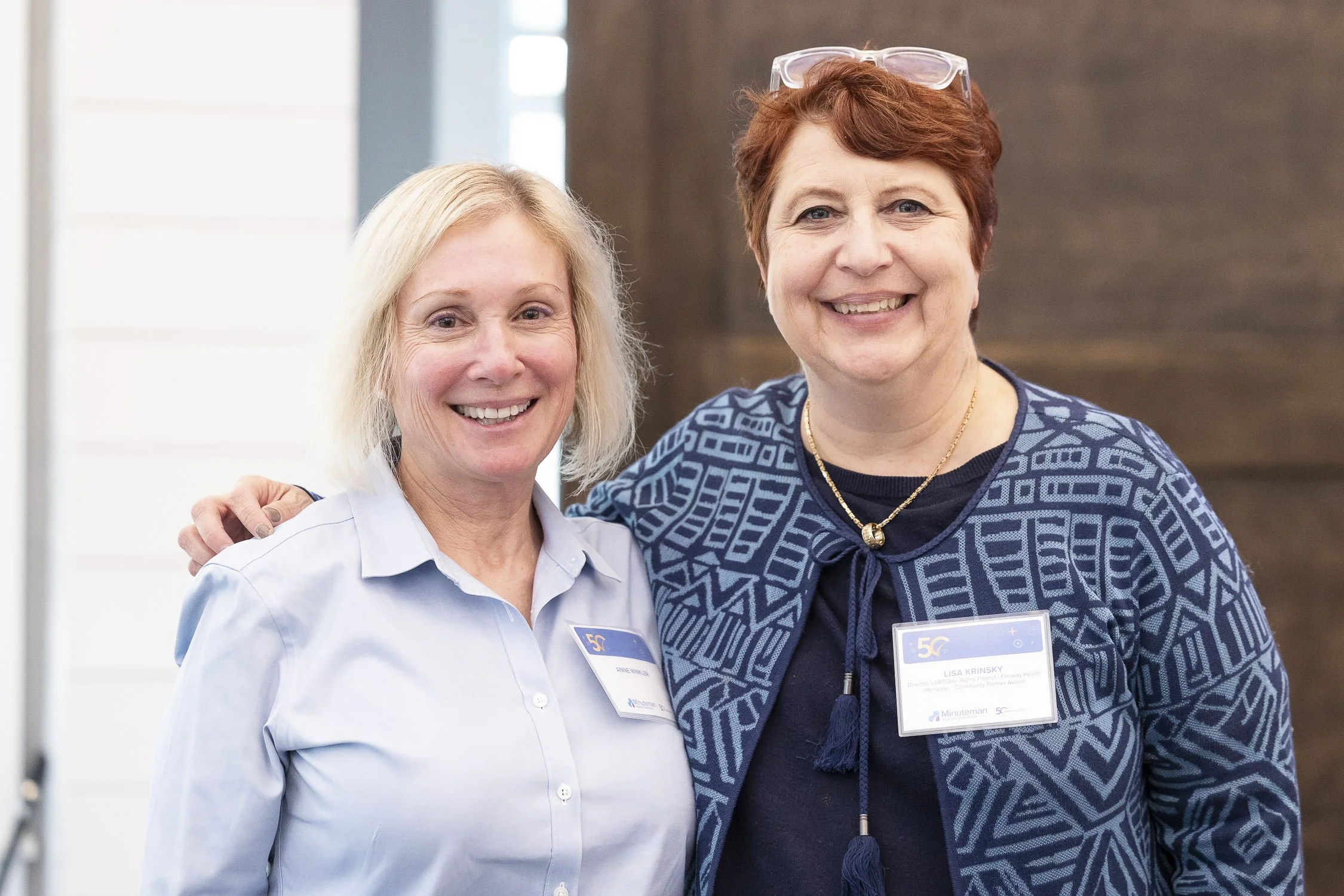 Two women smiling wearing name tags at a nonprofit auction in Lincoln, Massachusetts.