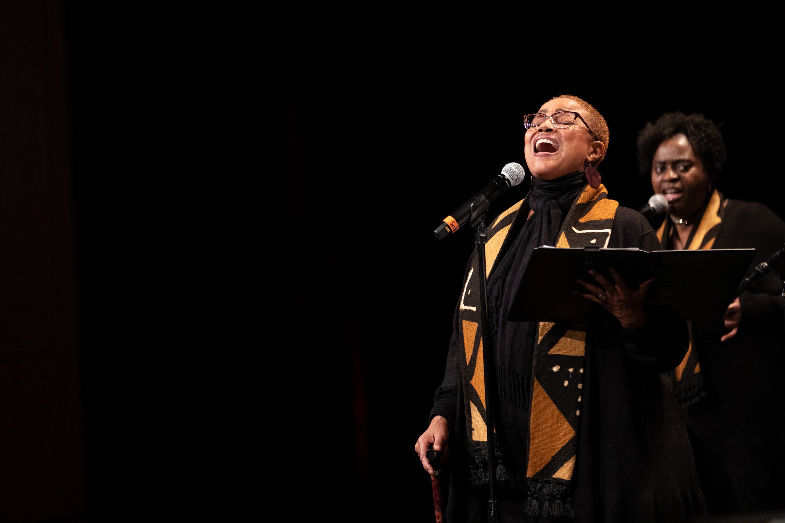 Two women perform on stage singing gospel music at an event in Boston, Massachusetts.
