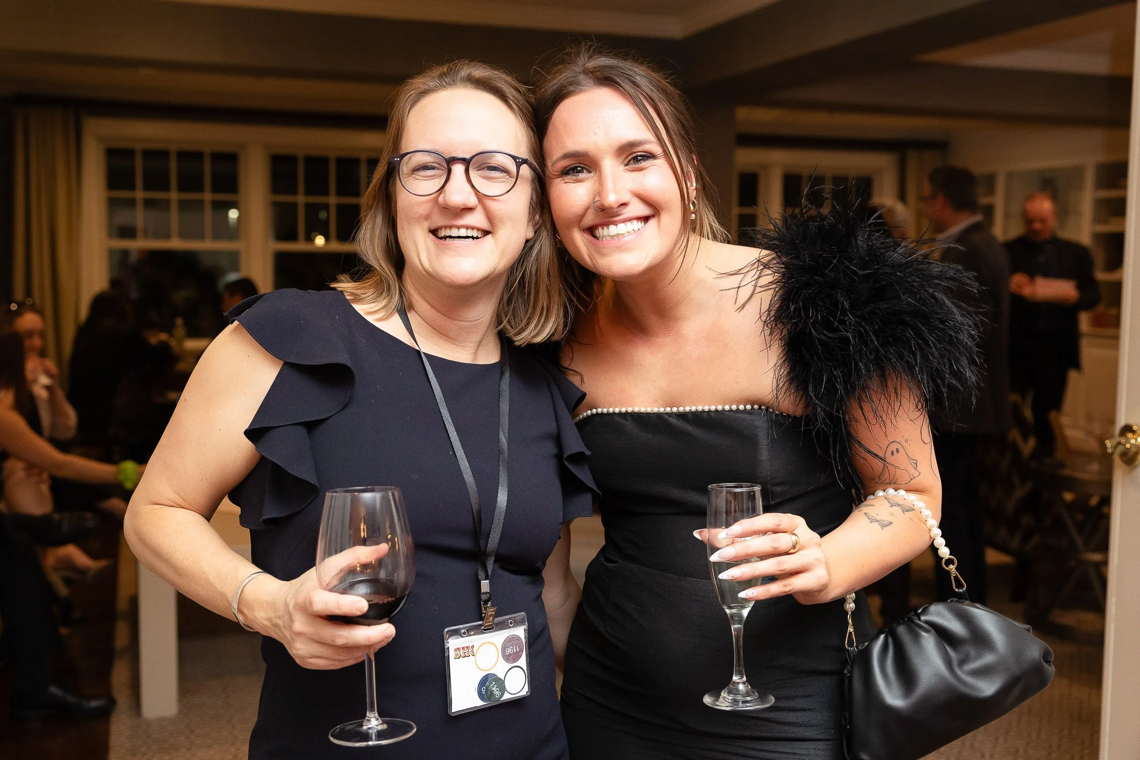 Two women smiling and posing together at a social event indoors in Newton, Massachusetts.