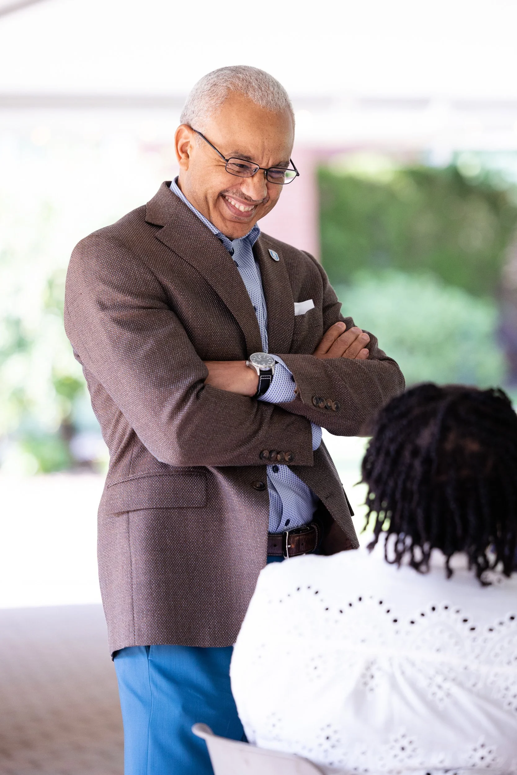 The president of Bentley University engaging in conversation with a seated woman.