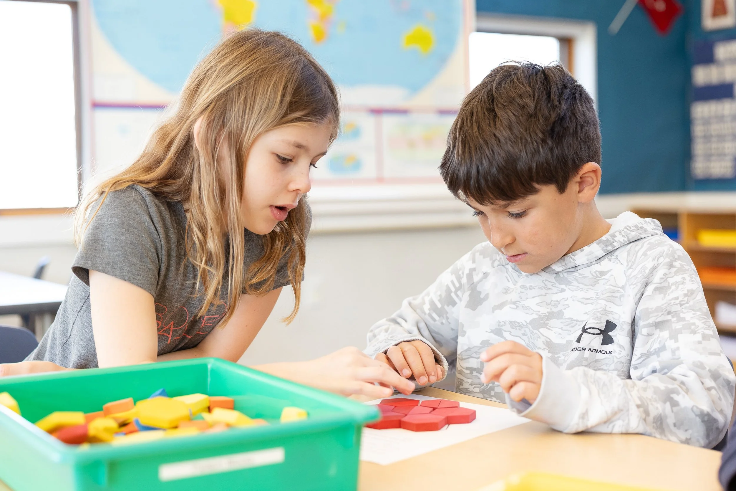 Two children, engaged in a learning activity at a classroom table at Charles River School in Dover.
