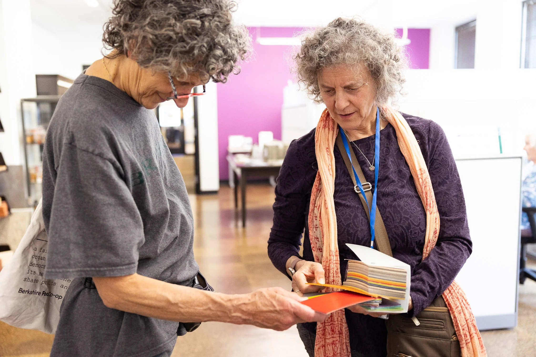Two women with curly gray hair looking at color samples together.