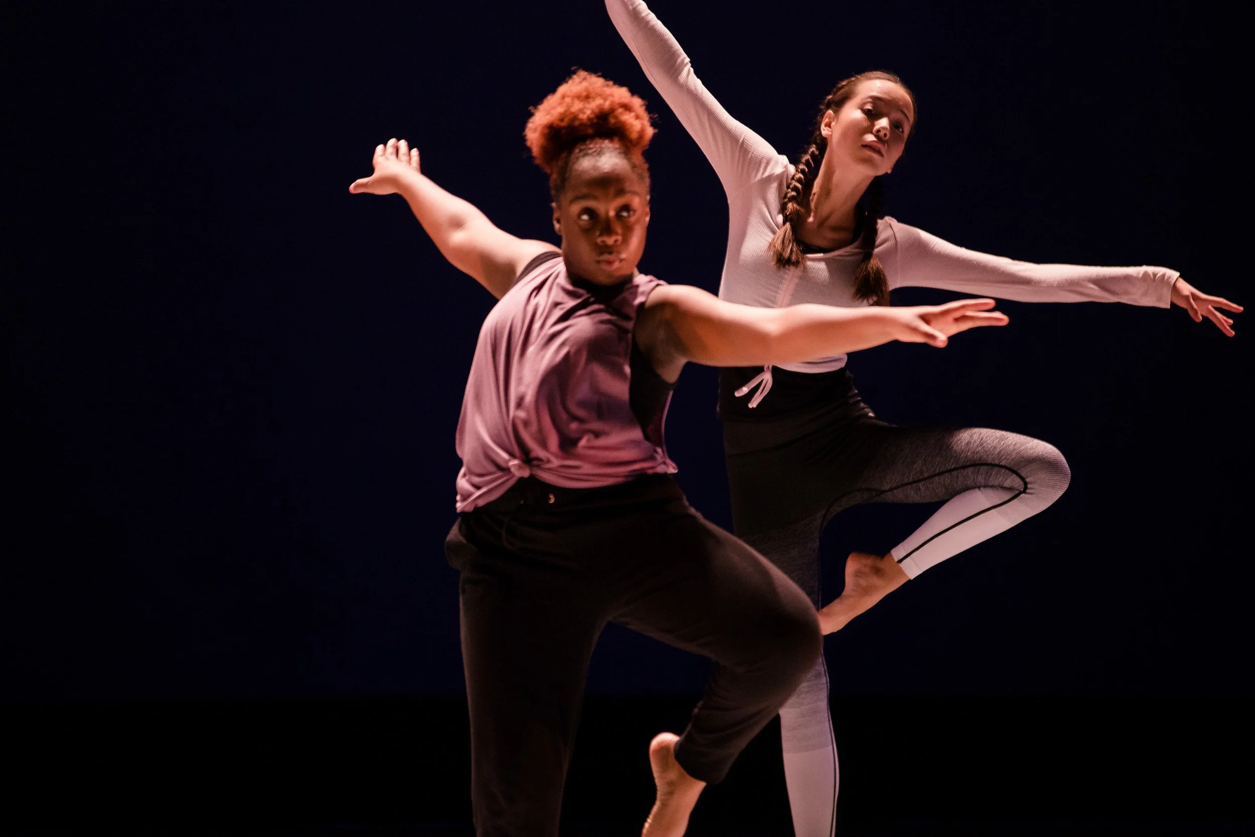 Two dancers perform on stage in a high school dance performance.
