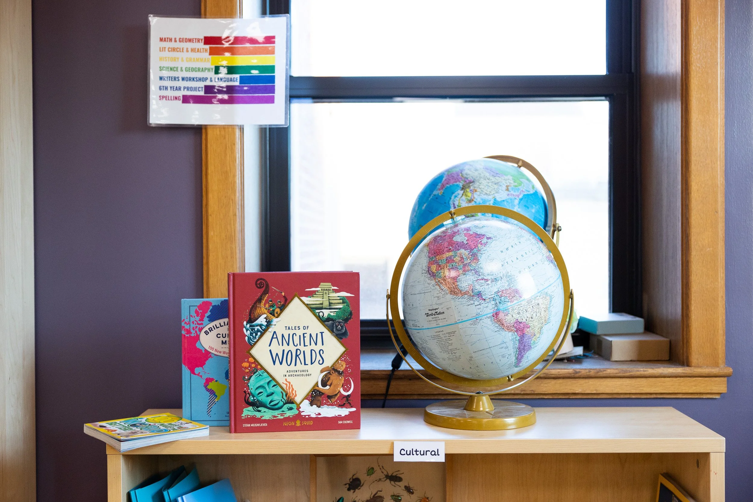 A Montessori classroom bookcase with educational books and two globes.