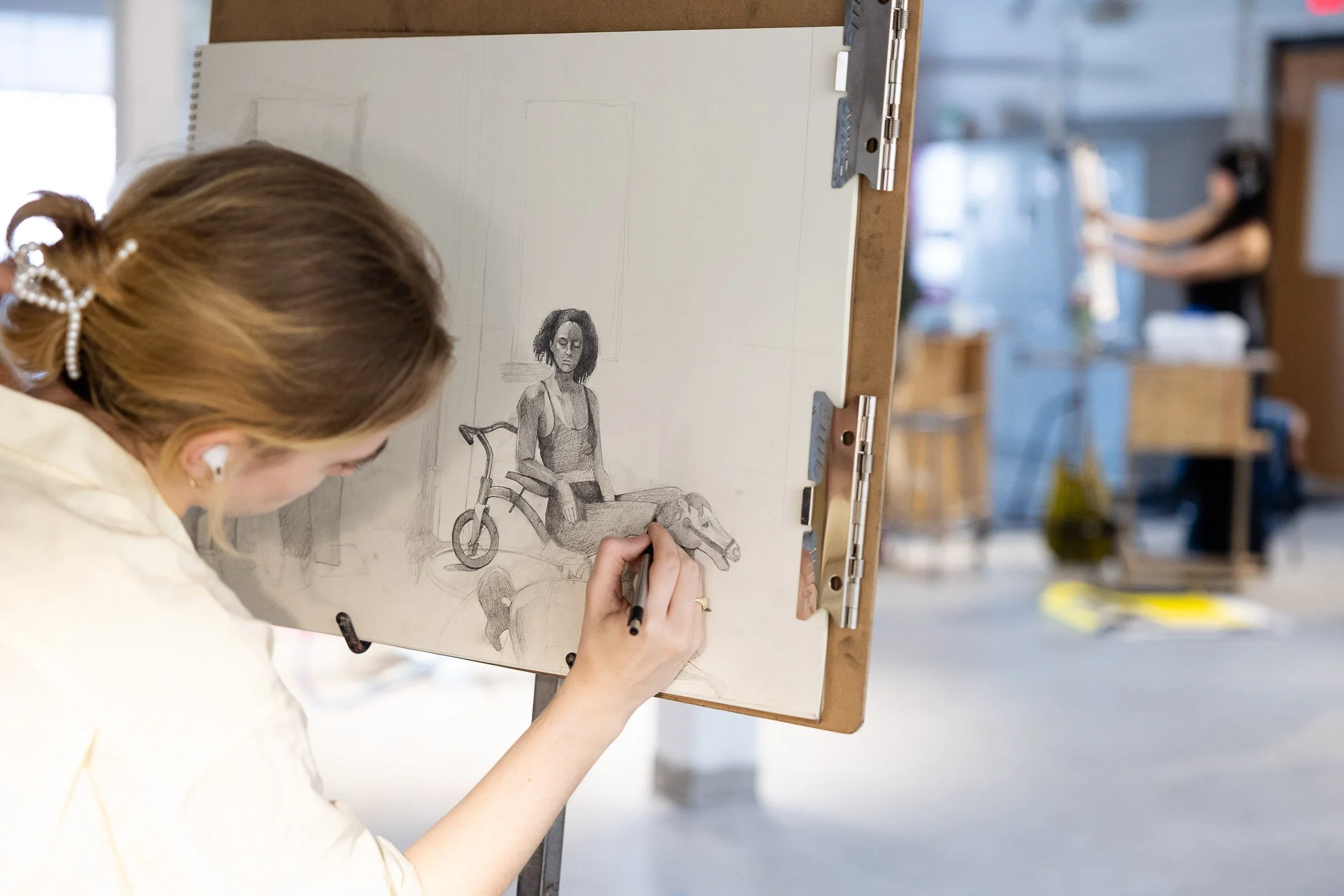 Artist drawing on a sketchpad in a college art studio.