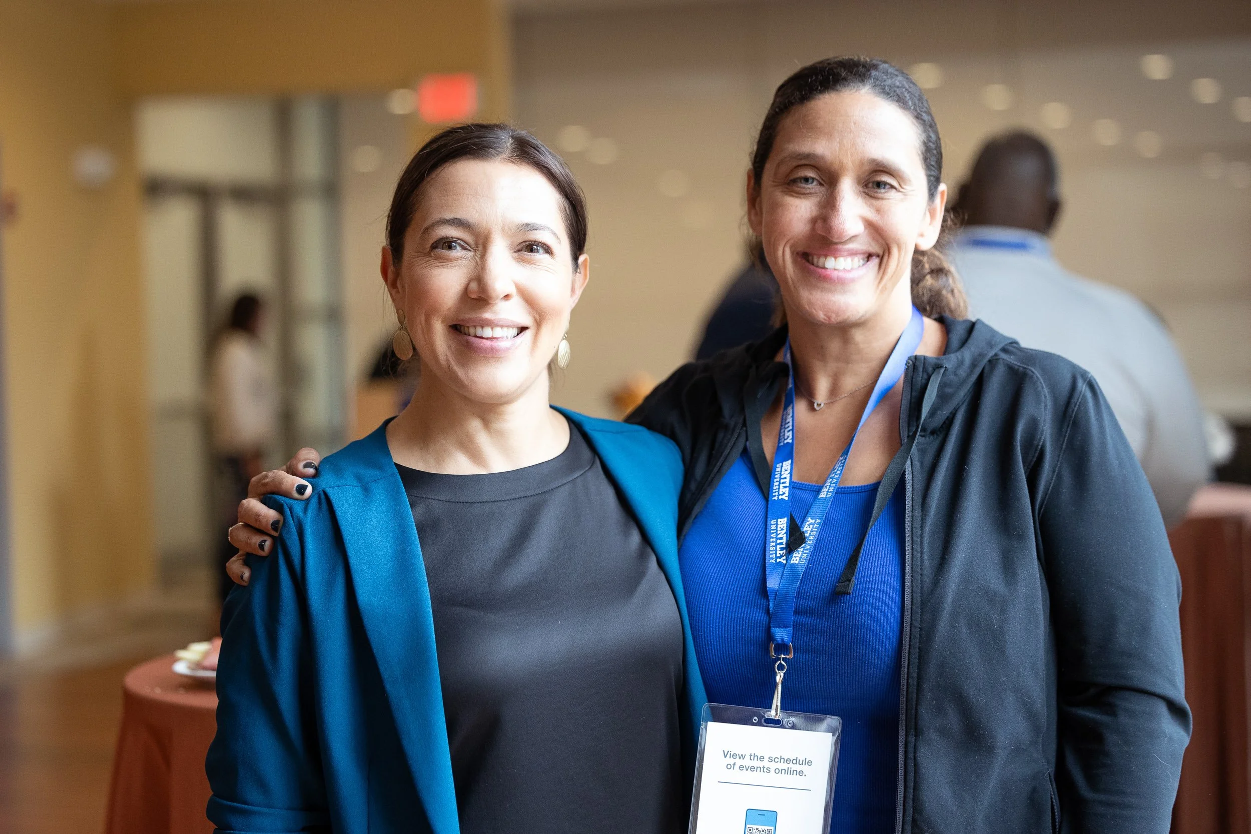 Two women smiling at a Bentley University social event.