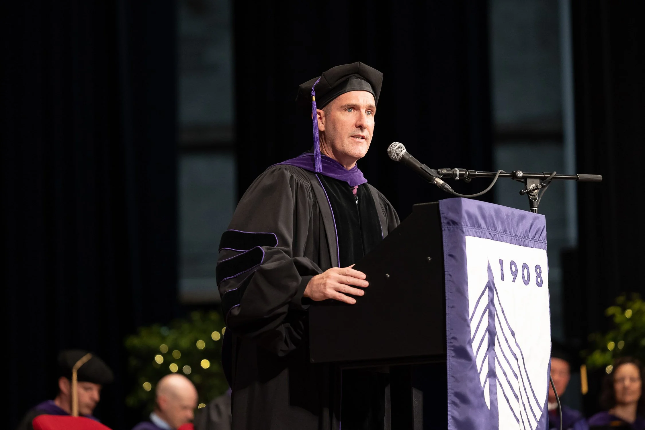 A man speaking at a podium during a graduation ceremony for Boston law school.