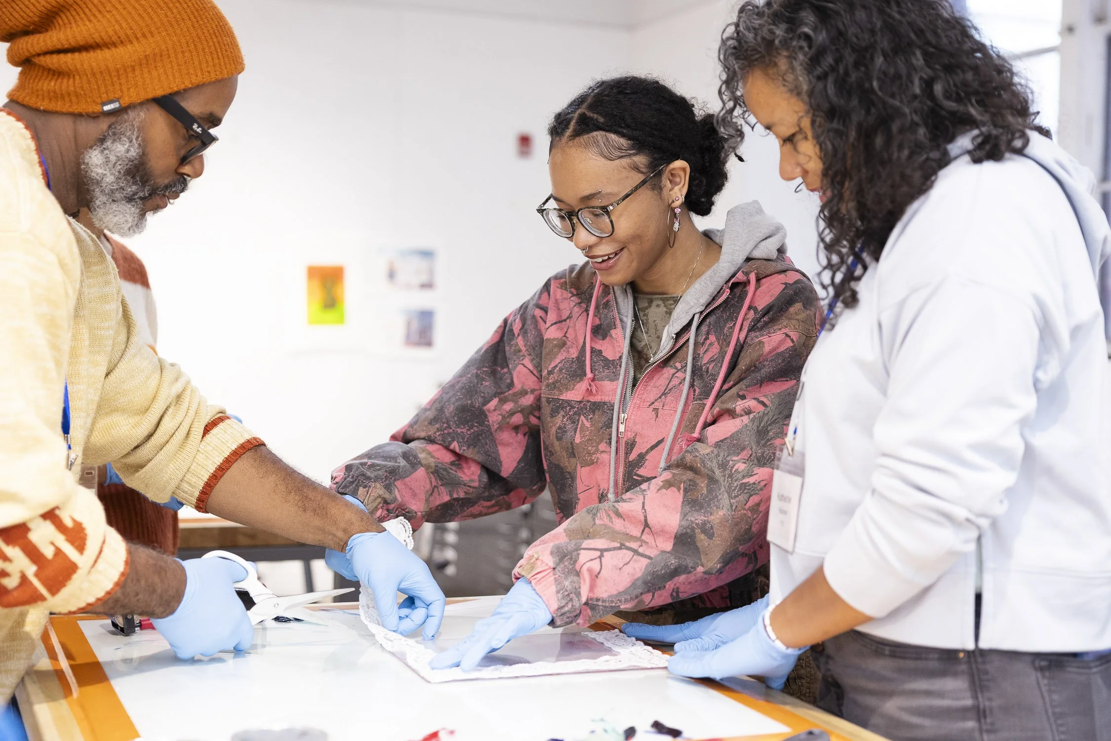Three people working together on an art project at a workshop in Boston.
