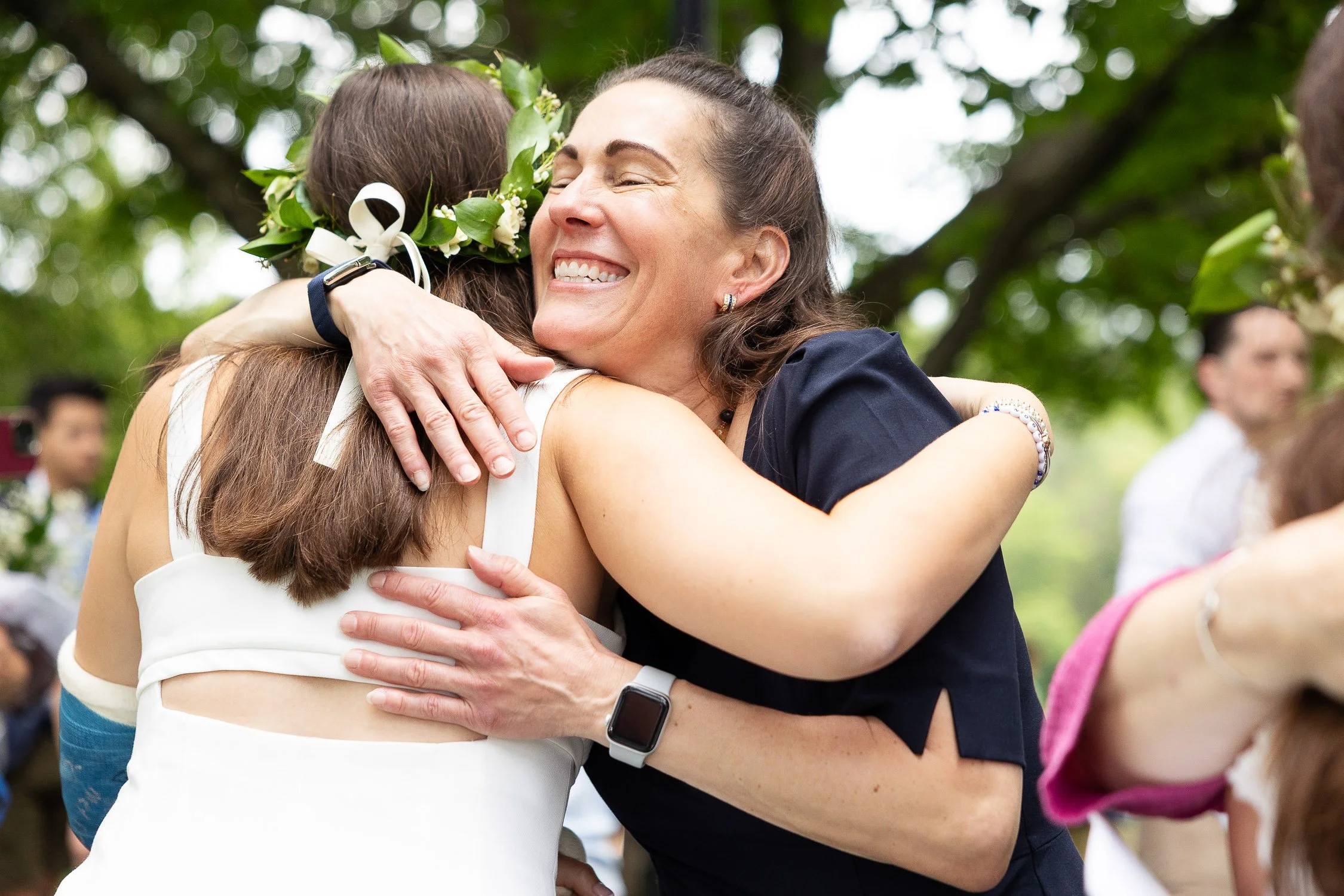 Two women hugging at an outdoor graduation celebration at Noble and Greenough school.