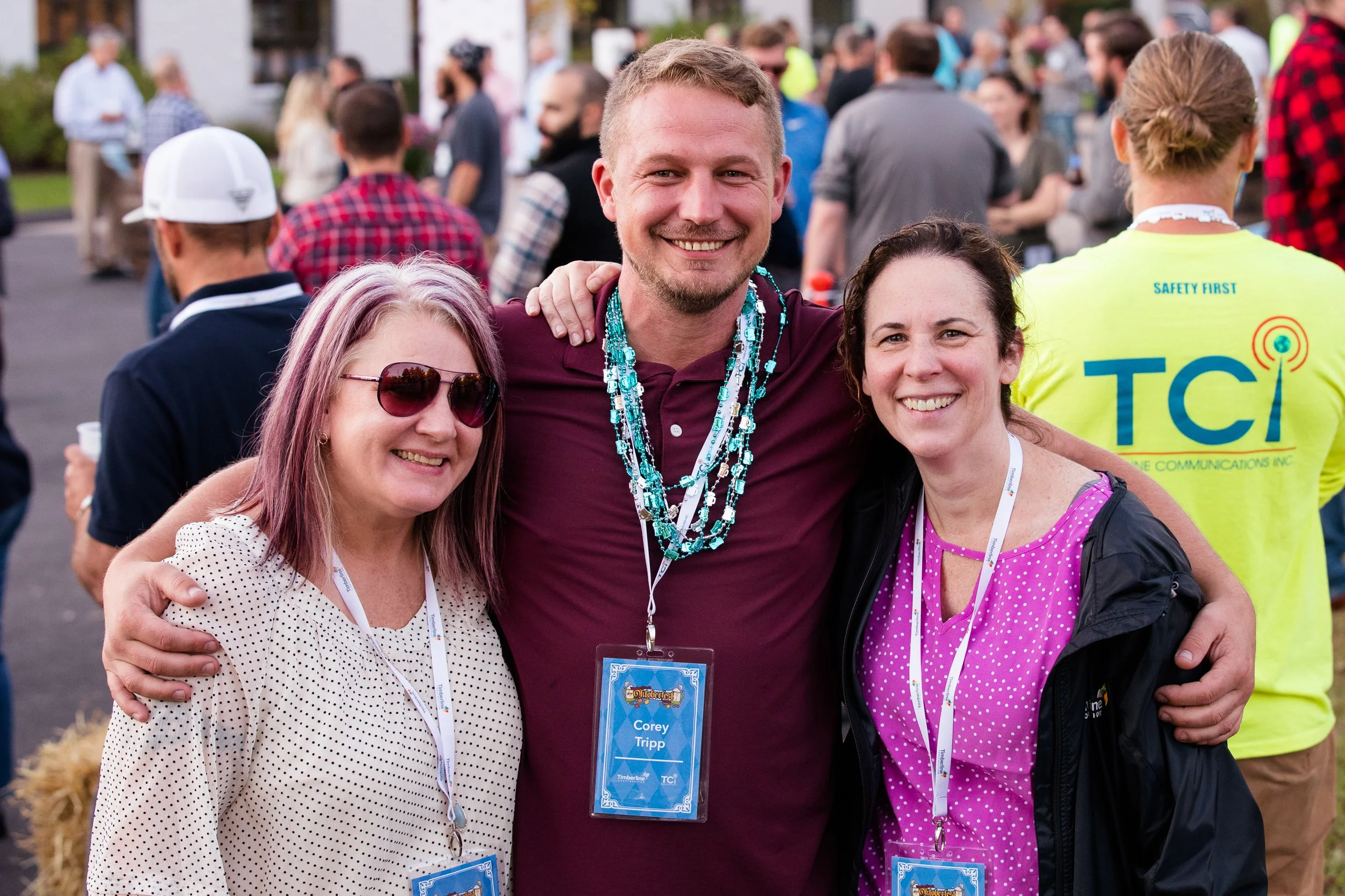 Three people smiling and posing for a photo at an outdoor company event.