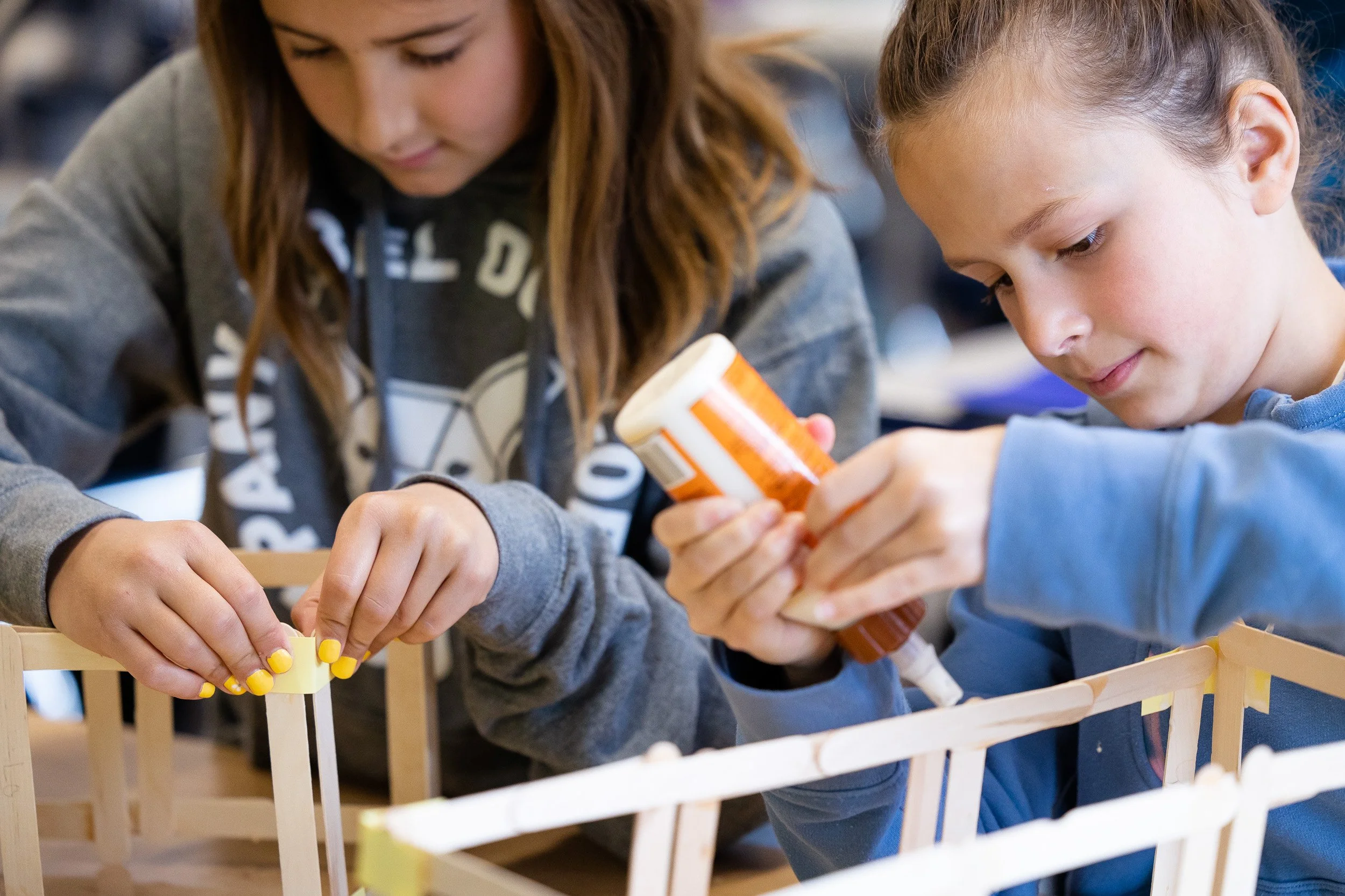 Two children working together on a wooden craft project at a table at a Massachusetts private school.