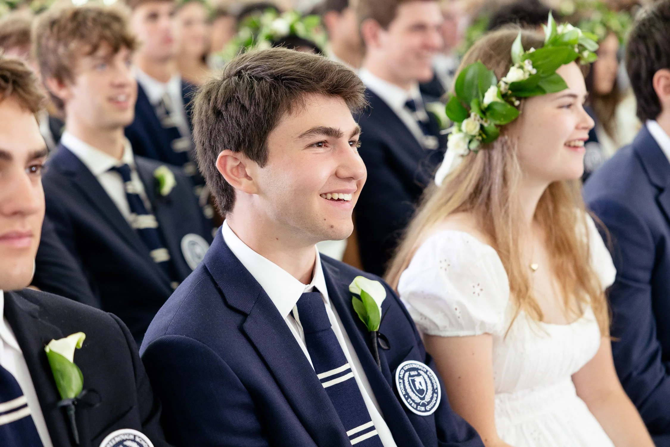 Students in formal attire attending a graduation ceremony.