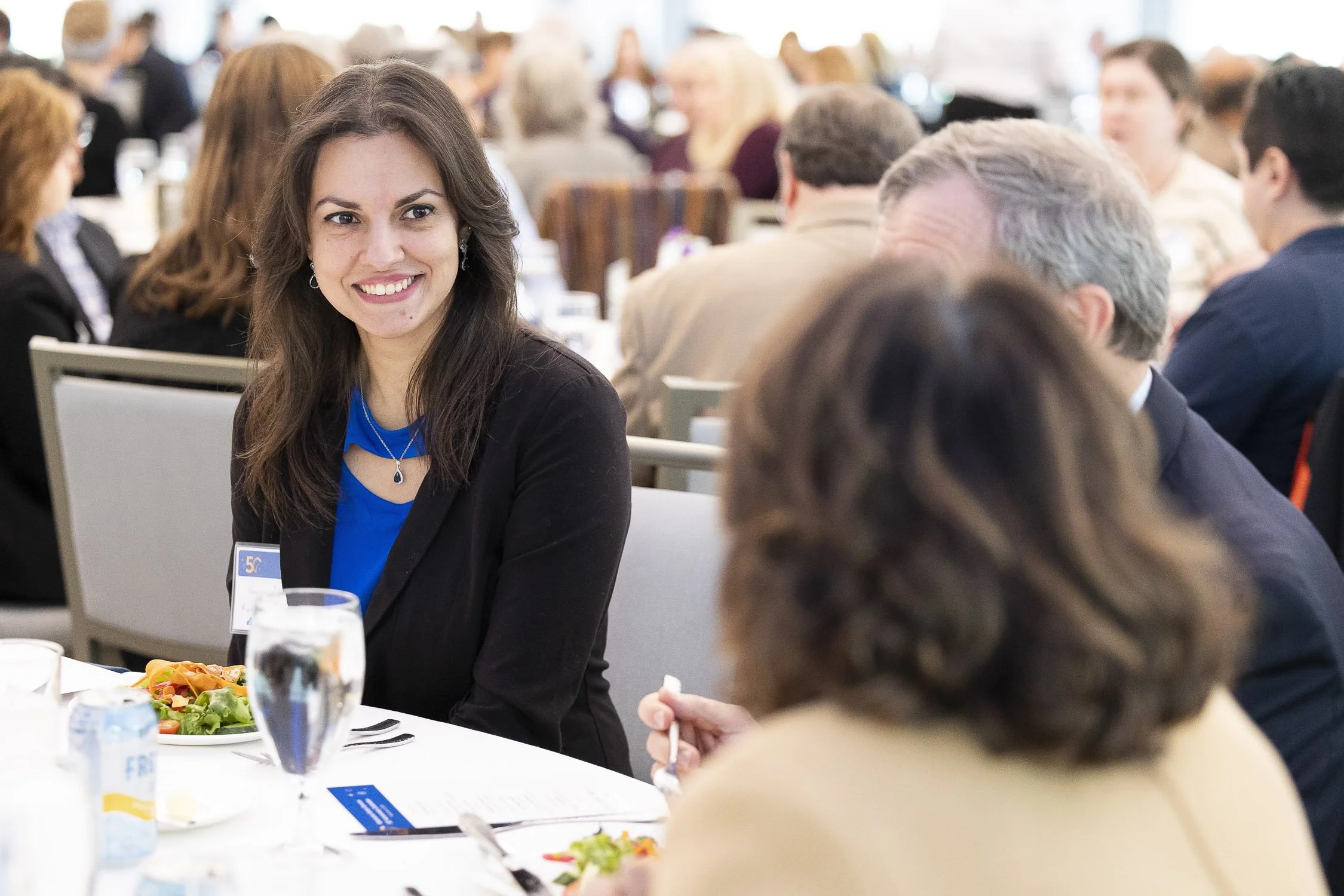 A woman seated at a table during a formal nonprofit event in Boston.
