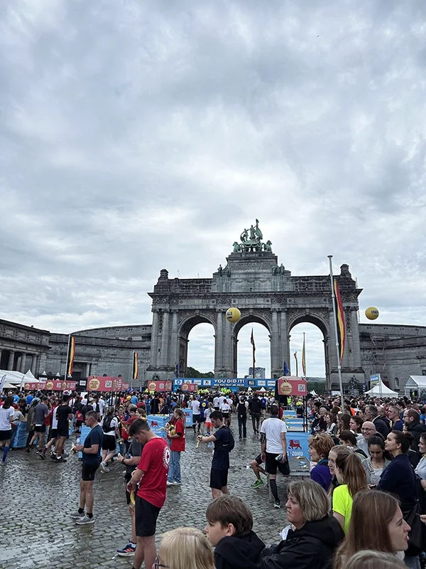 Evènement des 20km de Bruxelles devant le Cinquentenaire à Bruxelles, avec une foule de personnes et des stands, en journée nuageuse.