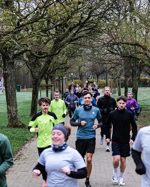 Groupe de personnes courant dans un parc avec des arbres, avec le run club Onyx basé à Stockel, Bruxelles, Belgique.
