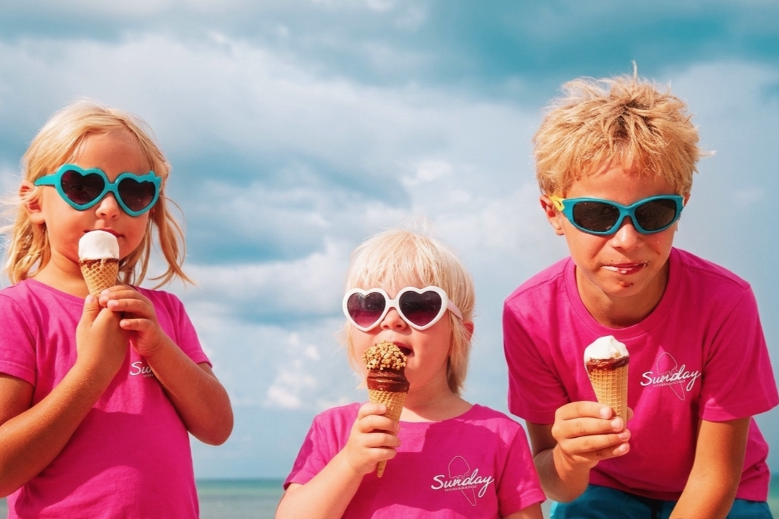 Children eating ice cream while wearing Sunday merchandise.