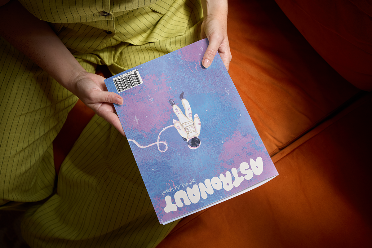 Woman holding a copy of the Astronaut zine.