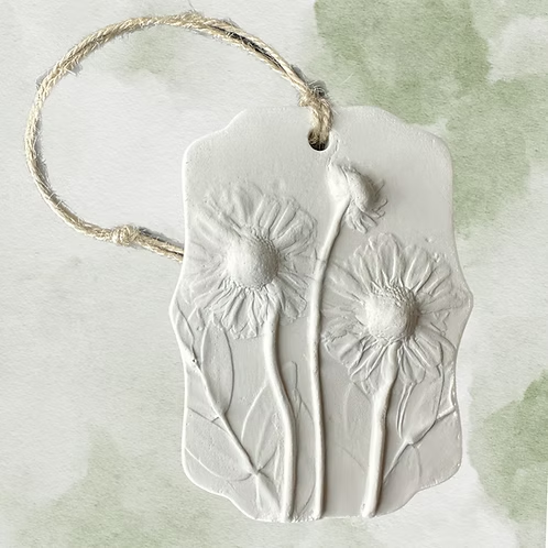 Botanical Bas Relief Essential Oil Diffuser with embossed daisies, a small mushroom shape, and a rope loop for hanging