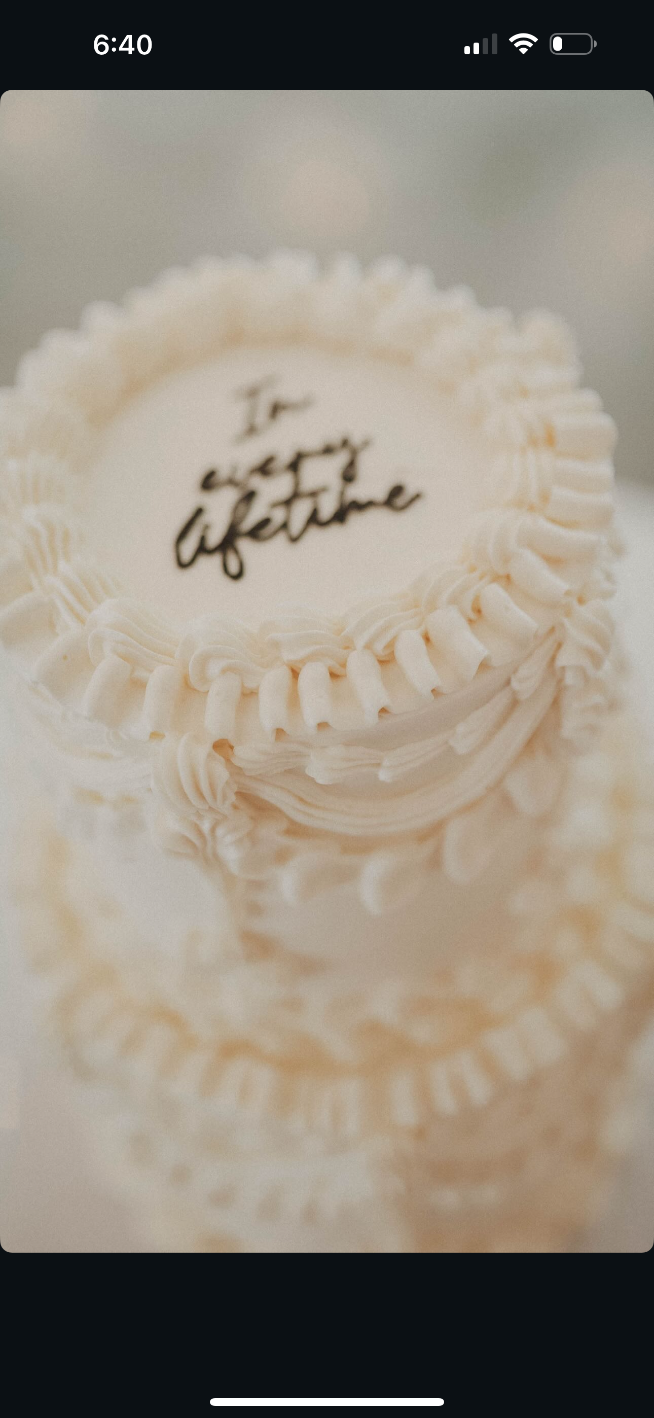 Decorative white cake with piped frosting and the handwritten message "To every lifetime" on the top.