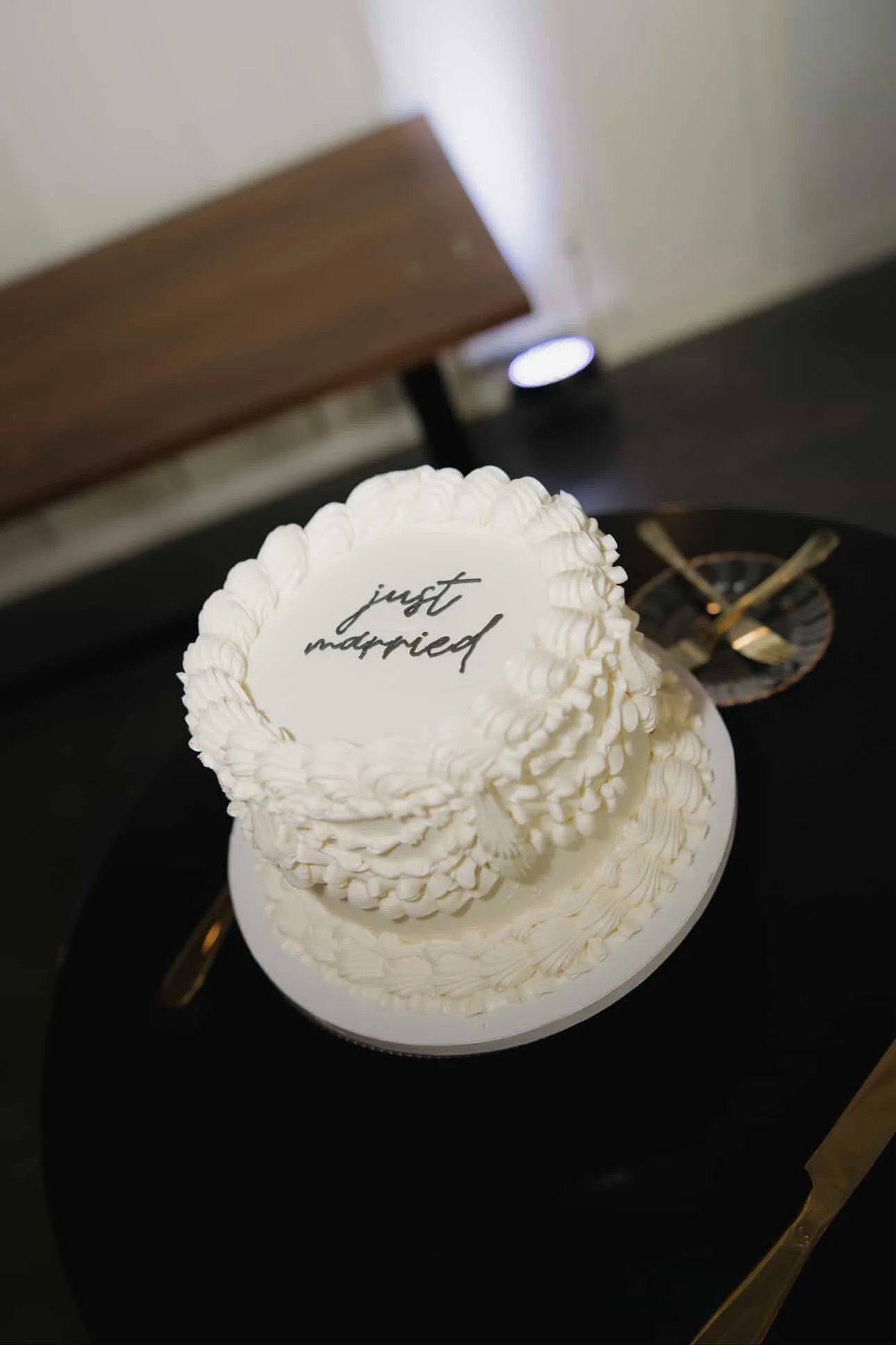 A white wedding cake with the words "just married" written on top, decorated with piped icing details.
