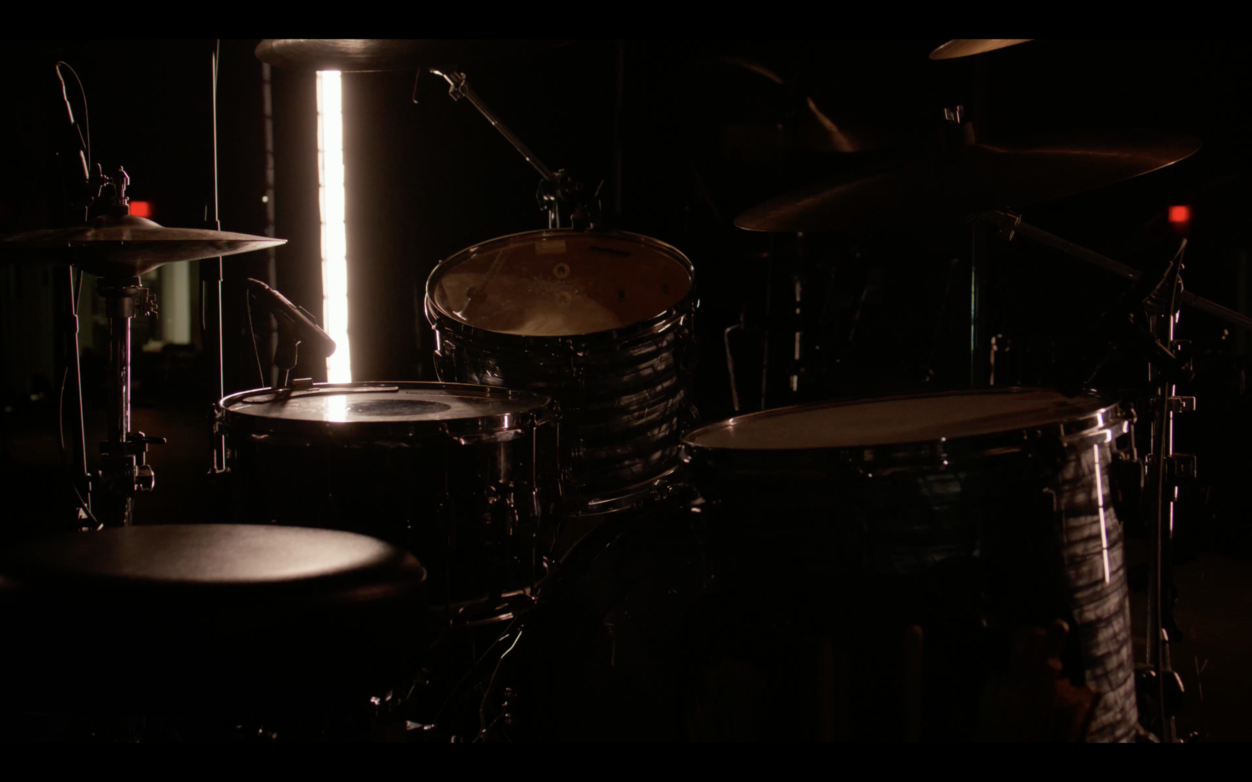 Dark image of drums and cymbals in a music studio with backlighting.