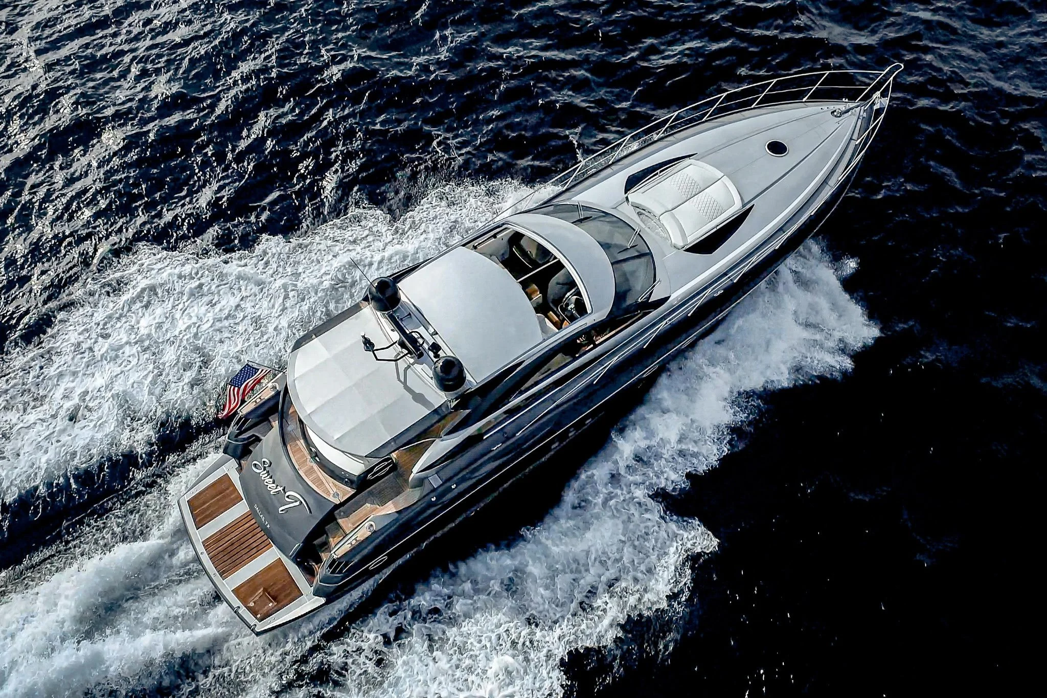 Aerial view of a luxury yacht sailing on the ocean with white waves trailing behind it