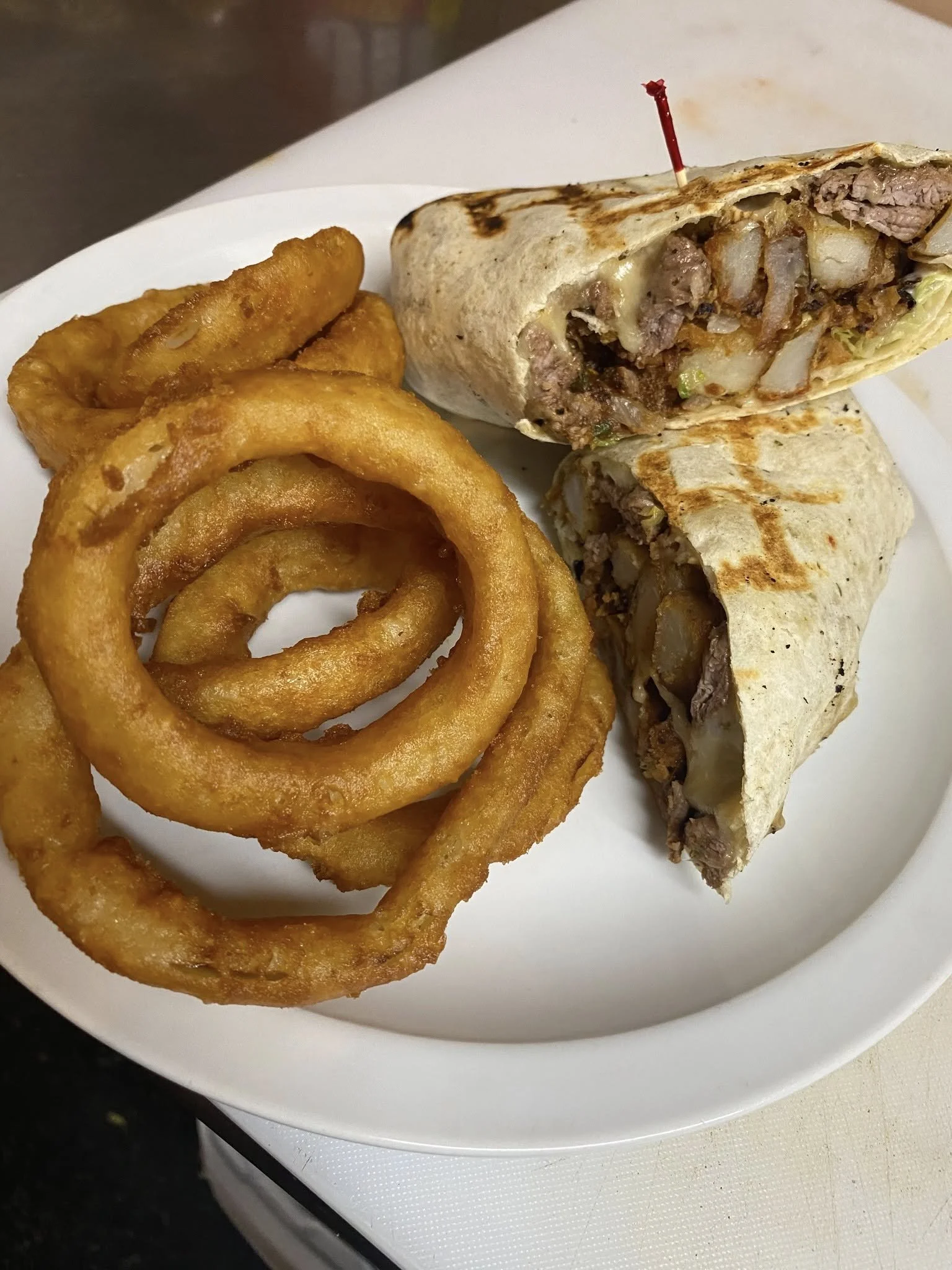 A plate of French fries and a beef and potato wrap sandwich.