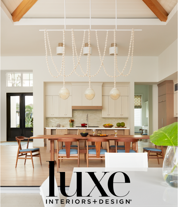 Modern open-concept kitchen and dining area with a wooden dining table, light-colored kitchen cabinets, and a decorative chandelier with rope loops and globe fixtures.