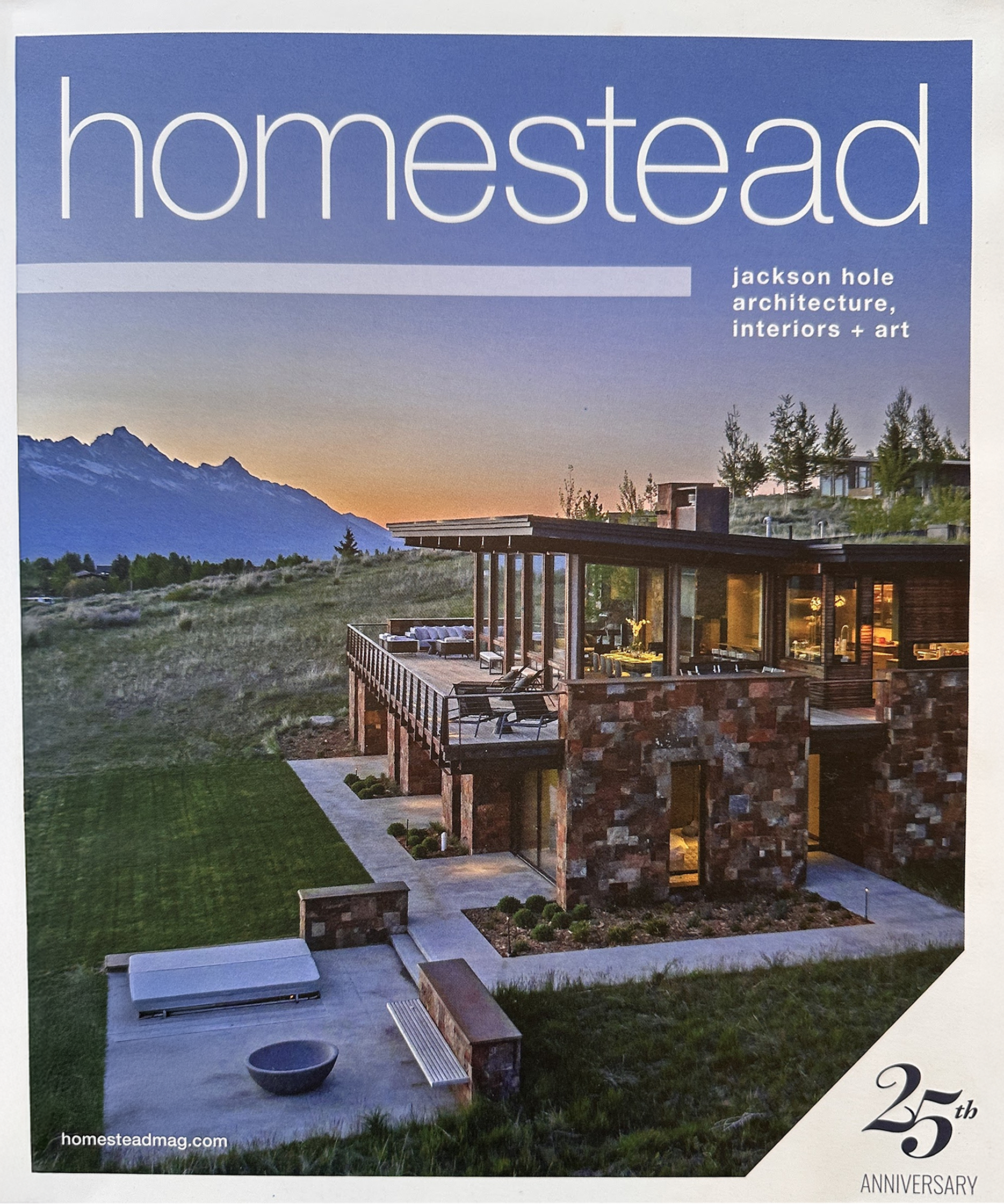 Front cover of Homestead magazine, showing a modern house with glass walls and a large balcony, set in a mountainous landscape at sunset.