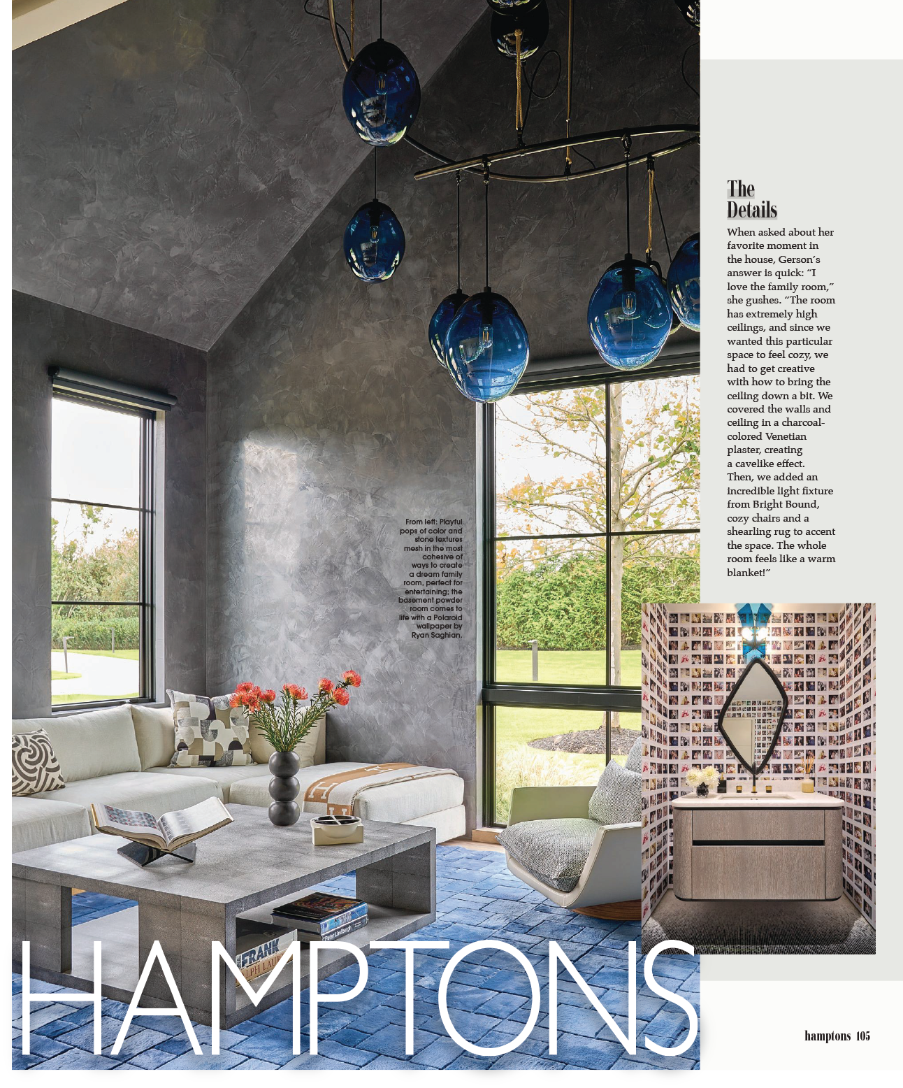 Interior view of a living room with textured gray walls, high ceilings, large windows showing a green outdoor landscape, and a modern chandelier with blue glass pendant lights. The space includes a white sectional sofa with patterned cushions, a gray