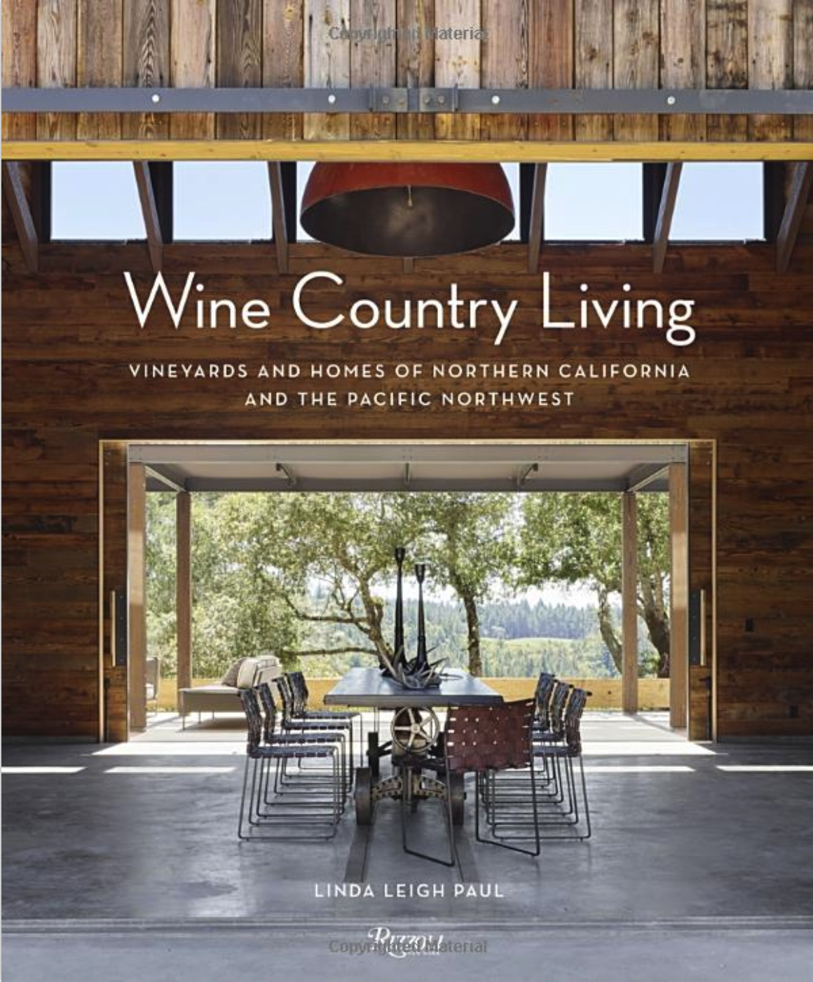 A book cover titled "Wine Country Living" featuring a rustic interior with a large wooden table and chairs, open to a view of trees and landscape outside.