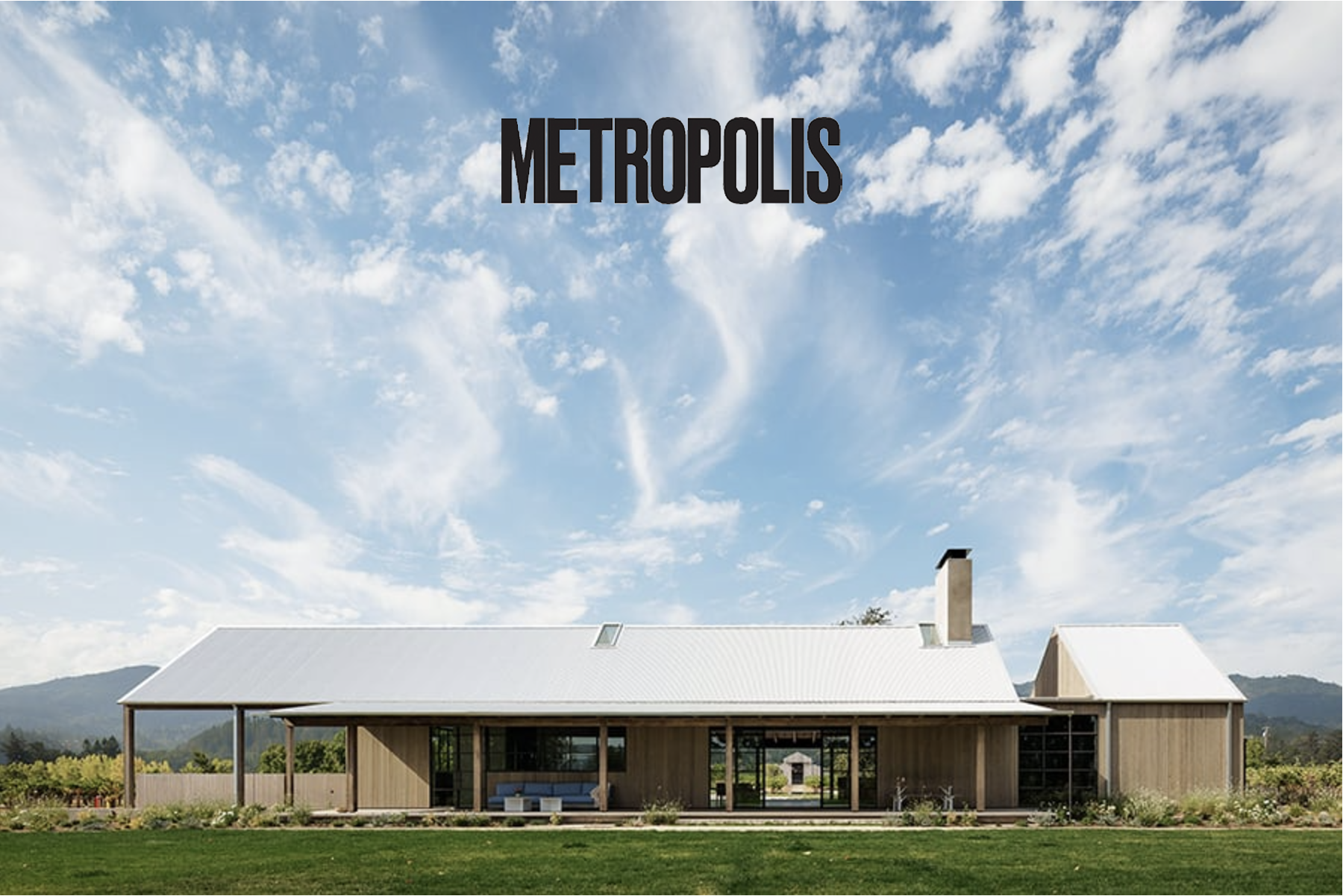 Modern house with a metal roof and large windows, surrounded by green grass, under a partly cloudy sky, with the word 'Metropolis' written at the top.
